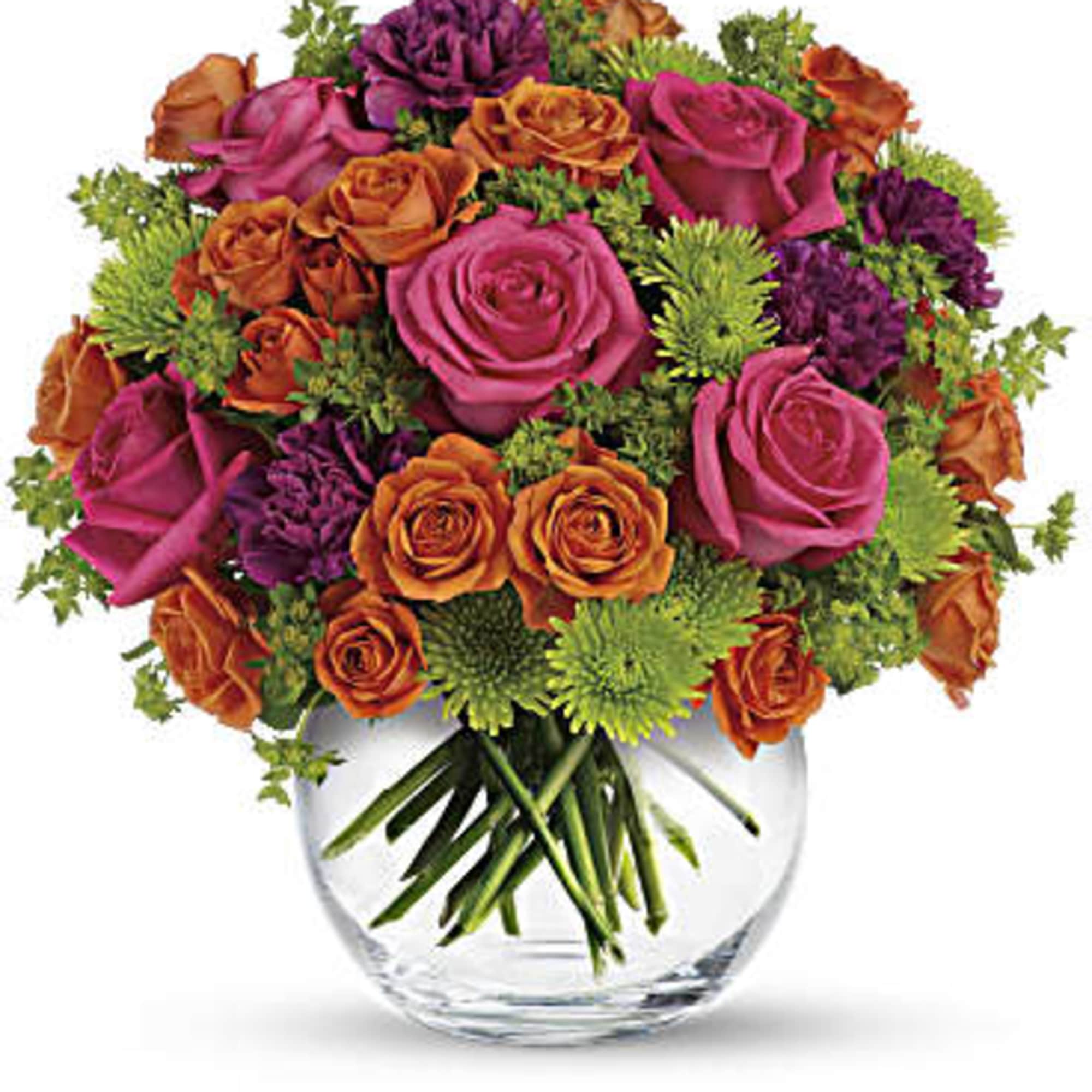 Pink and orange roses arranged in a clear glass vase