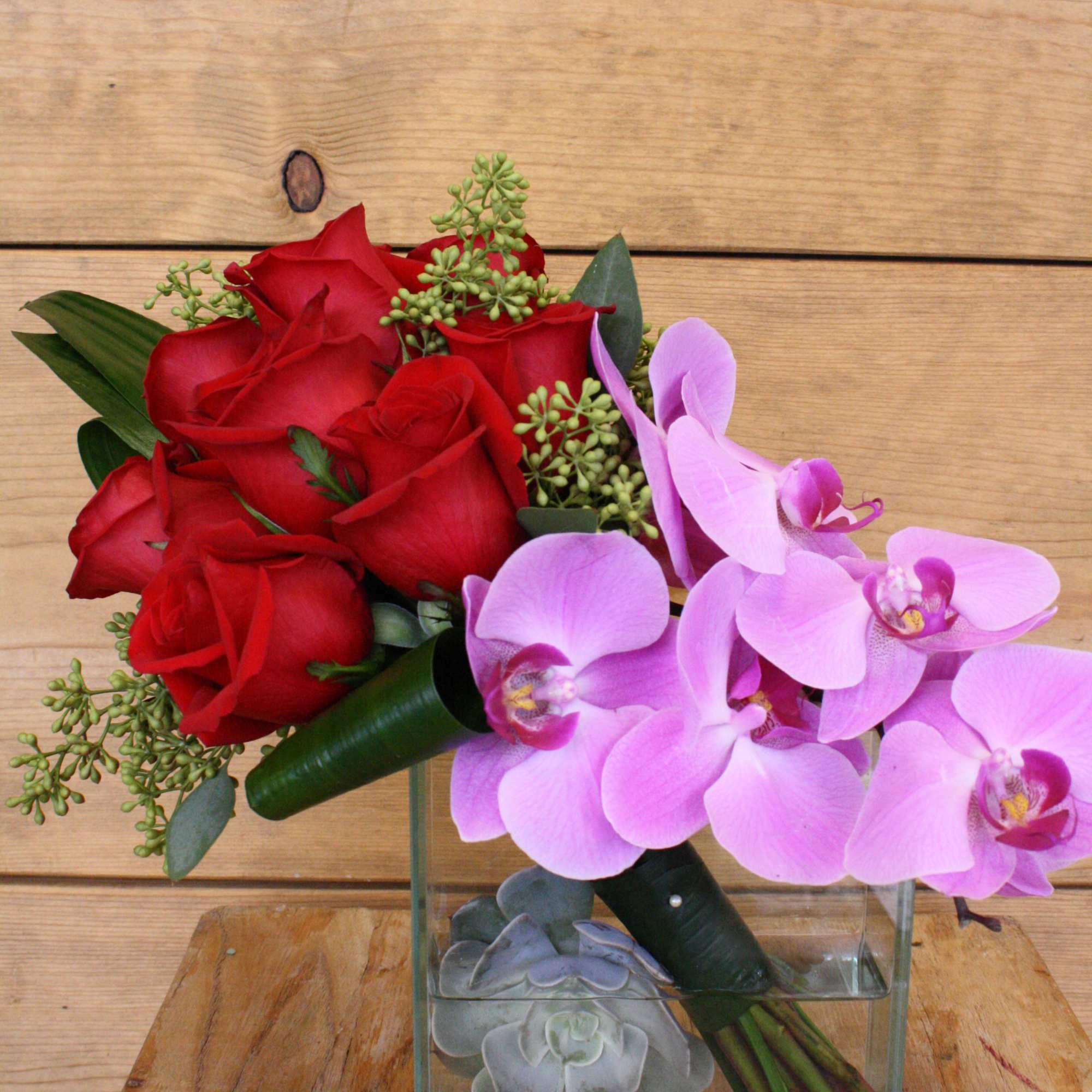 Red roses and pink orchids in a clear glass vase