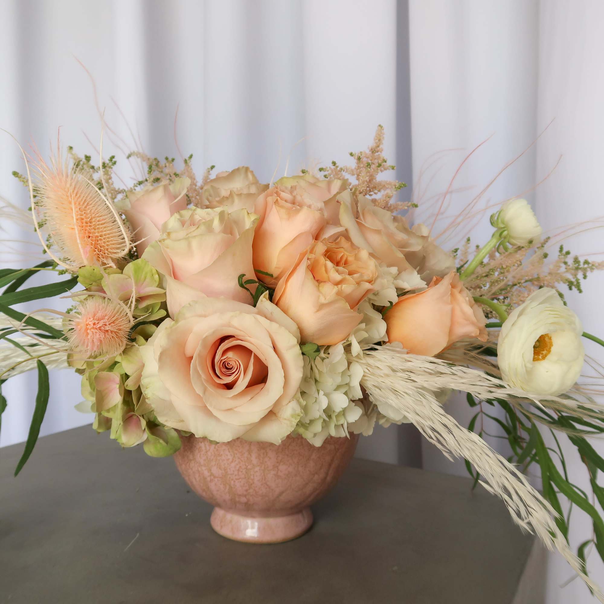 Peach roses and white ranunculus in a pink vase