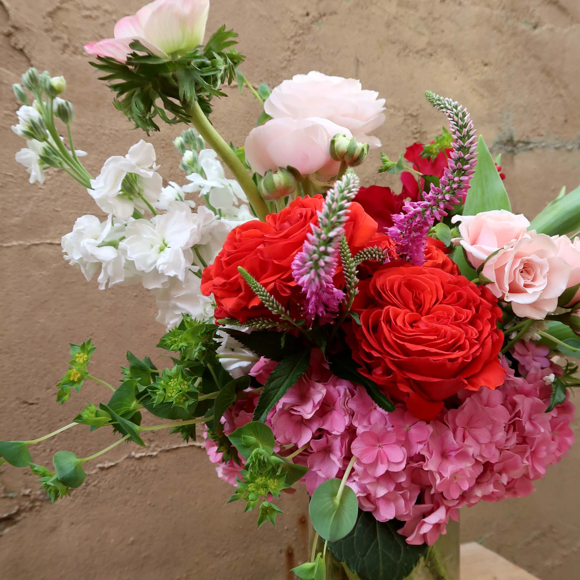 Mixed bouquet of red and pink roses with white blooms in a glass vase