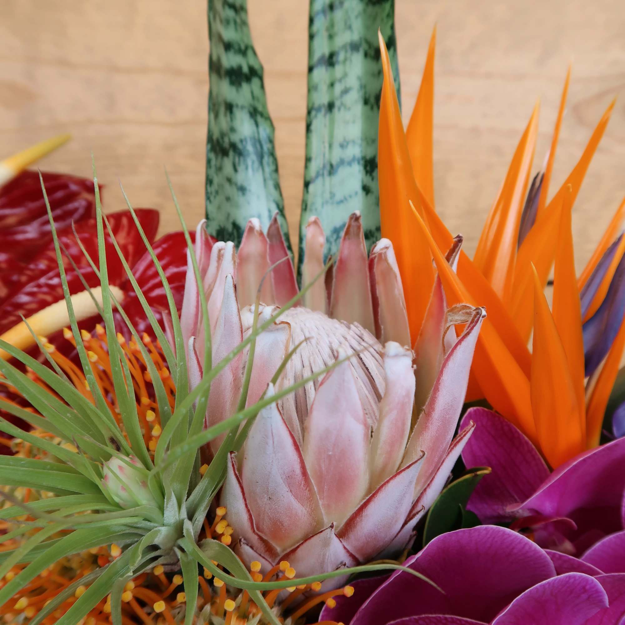 An assortment of tropical blooms in a brown ceramic vase, perfect to