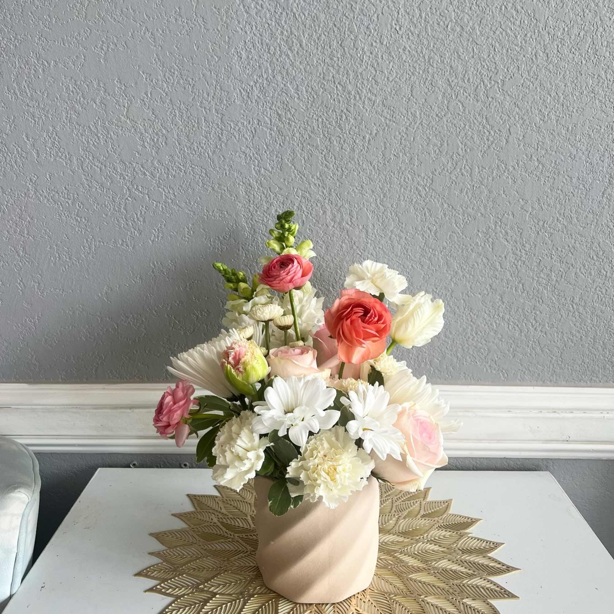 Pastel floral arrangement in a beige vase with pink, white, and peach blooms