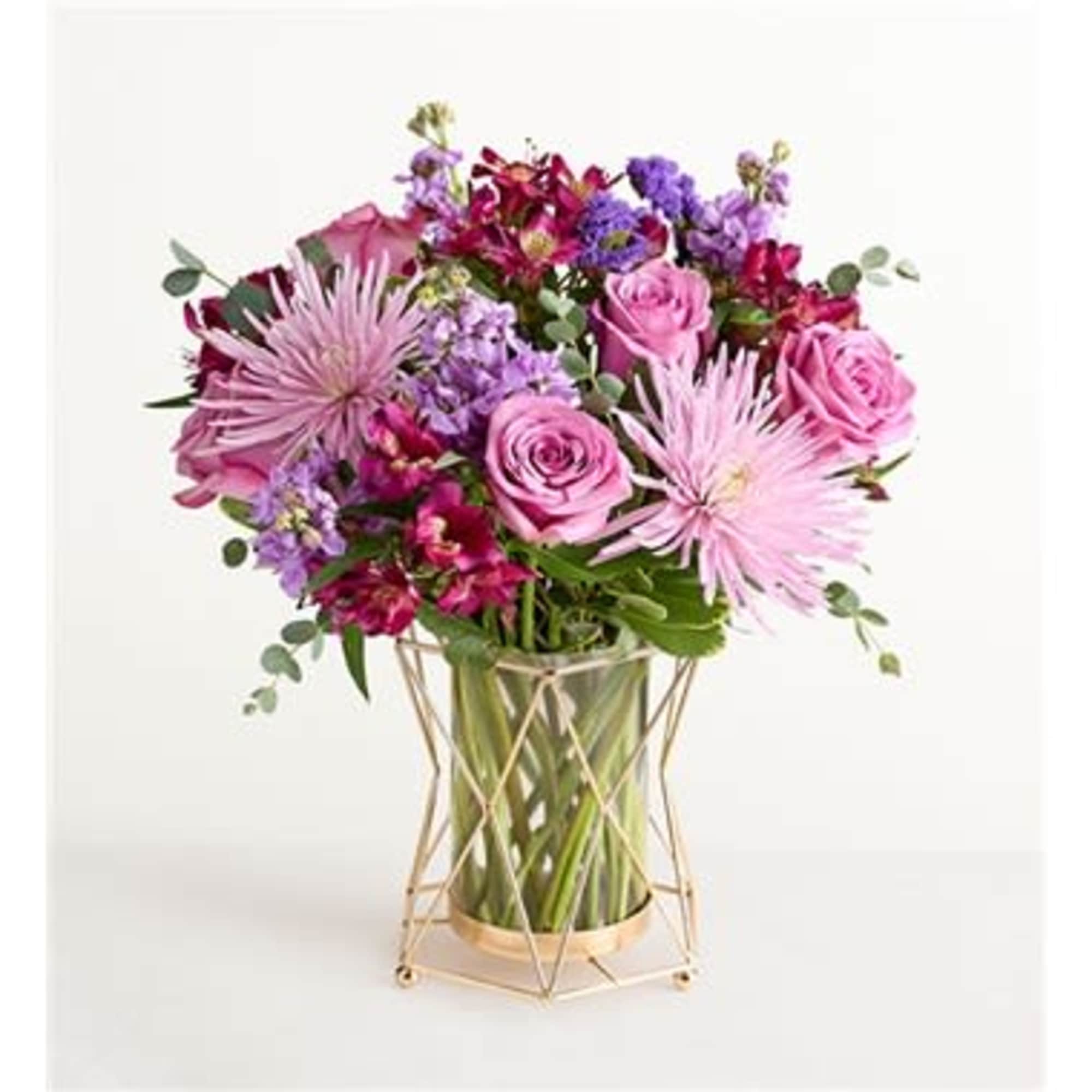 Pink and purple bouquet in a clear glass vase with a gold stand