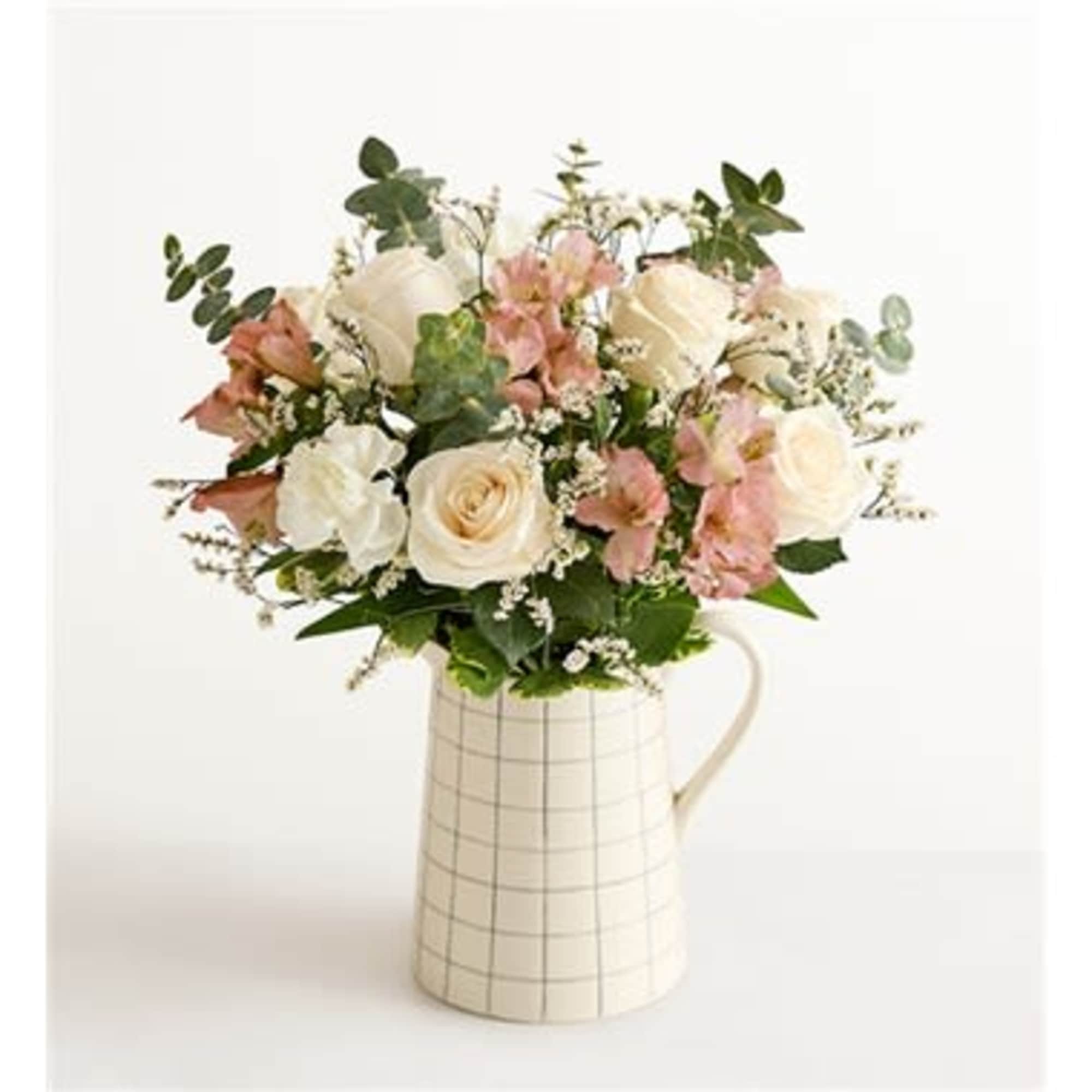 Bouquet of white and pink roses in a checked ceramic pitcher