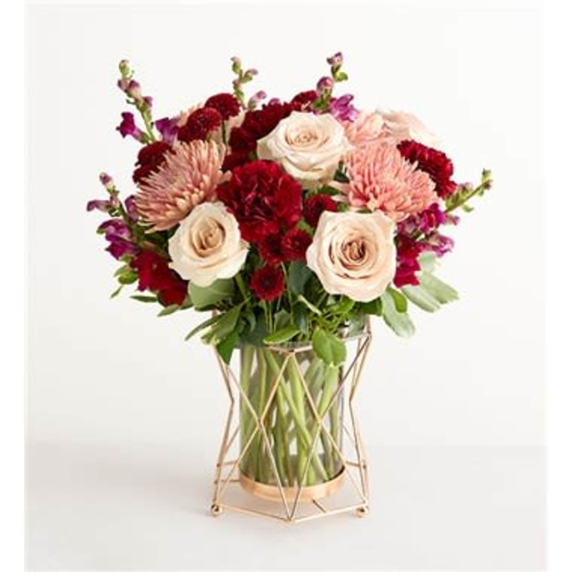 Bouquet of cream and red flowers in a geometric glass vase