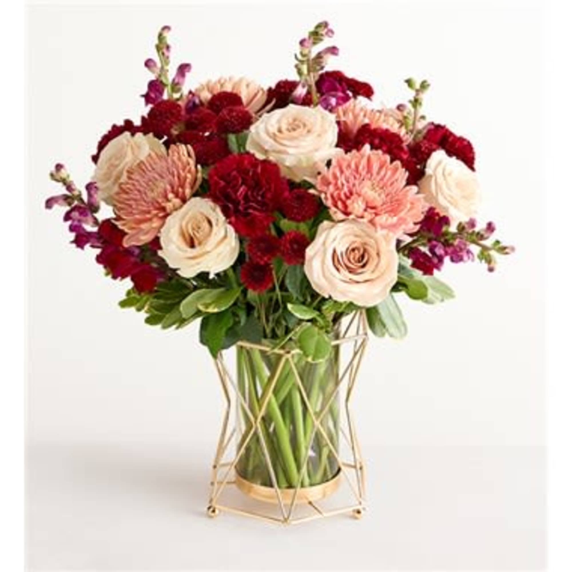 Bouquet of cream, blush, and red flowers in a gold geometric vase