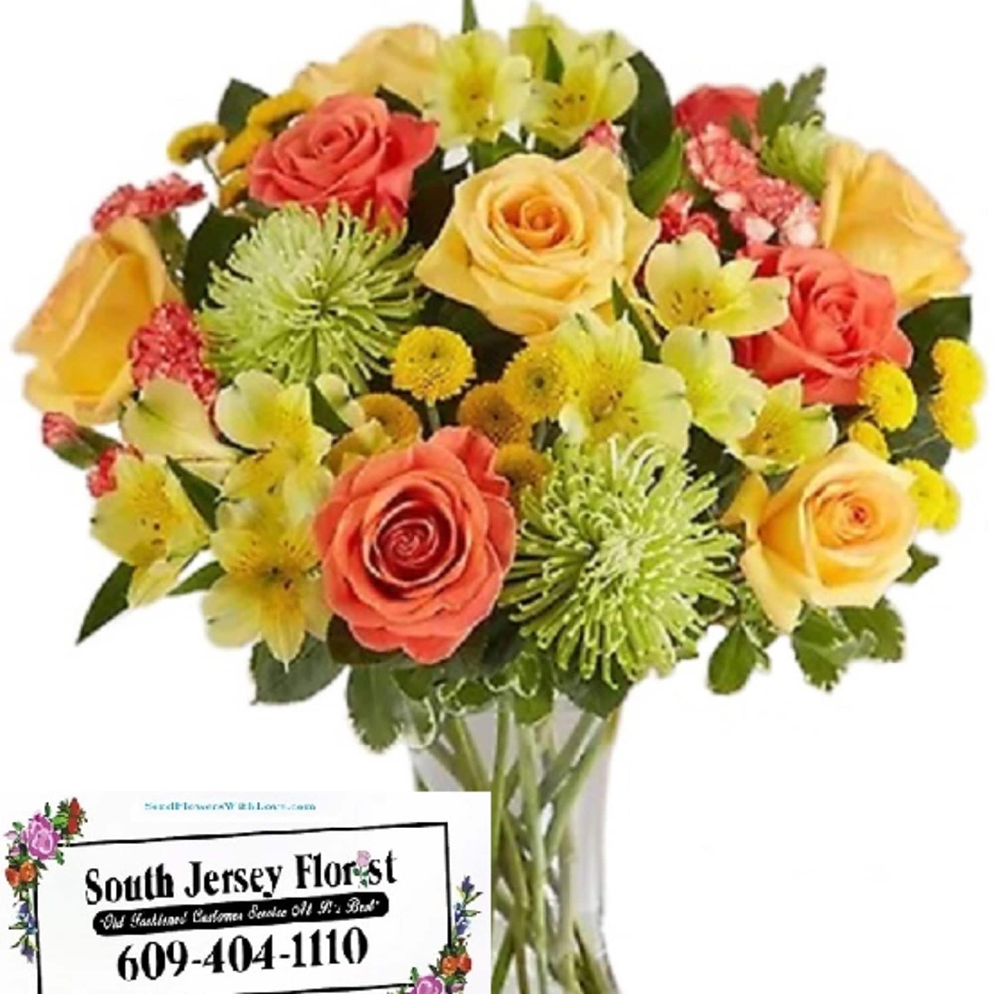 Bouquet of yellow and coral roses with green spider mums in a clear vase