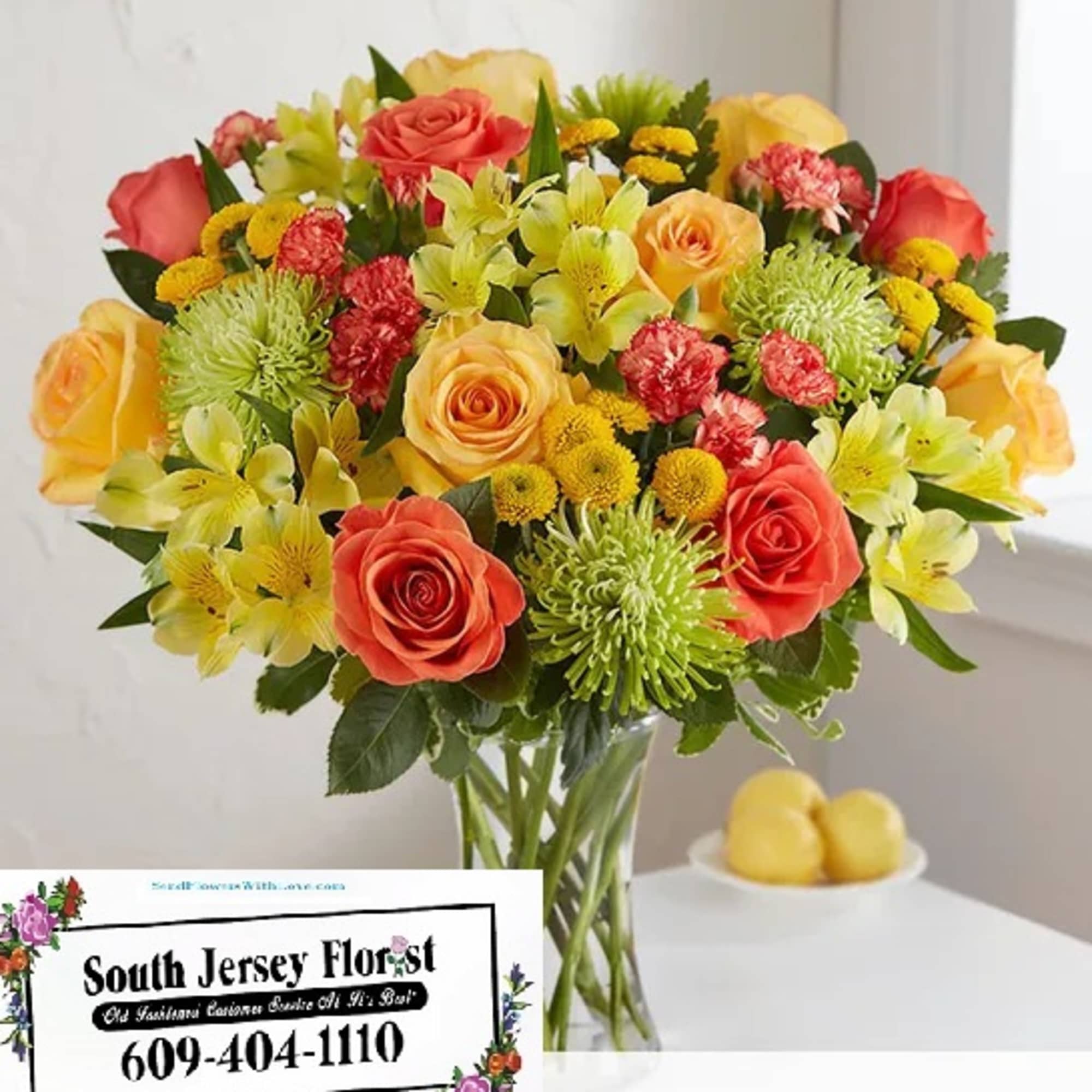 Mixed bouquet of roses, lilies, and chrysanthemums in a glass vase