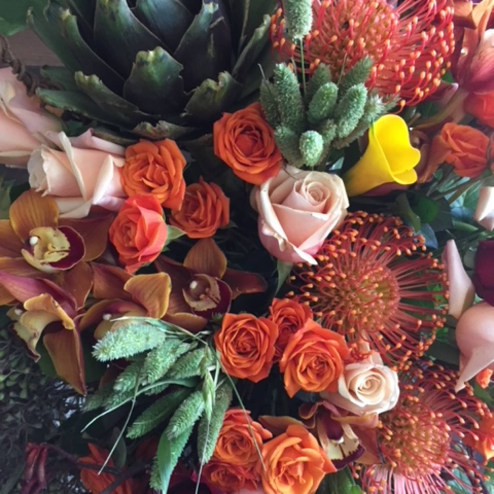 Bouquet of orange and blush roses with orchids and protea