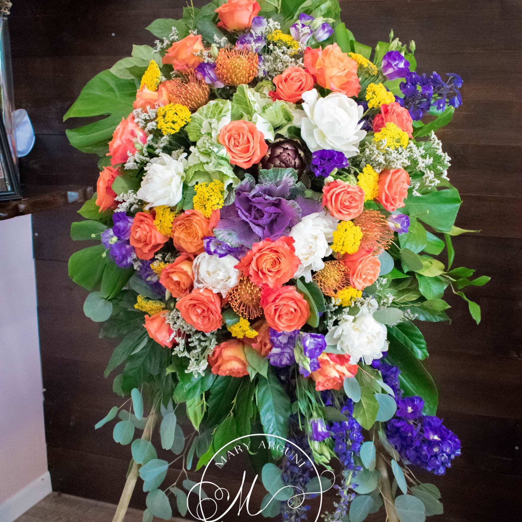 Large standing spray of orange, white, purple, and yellow flowers