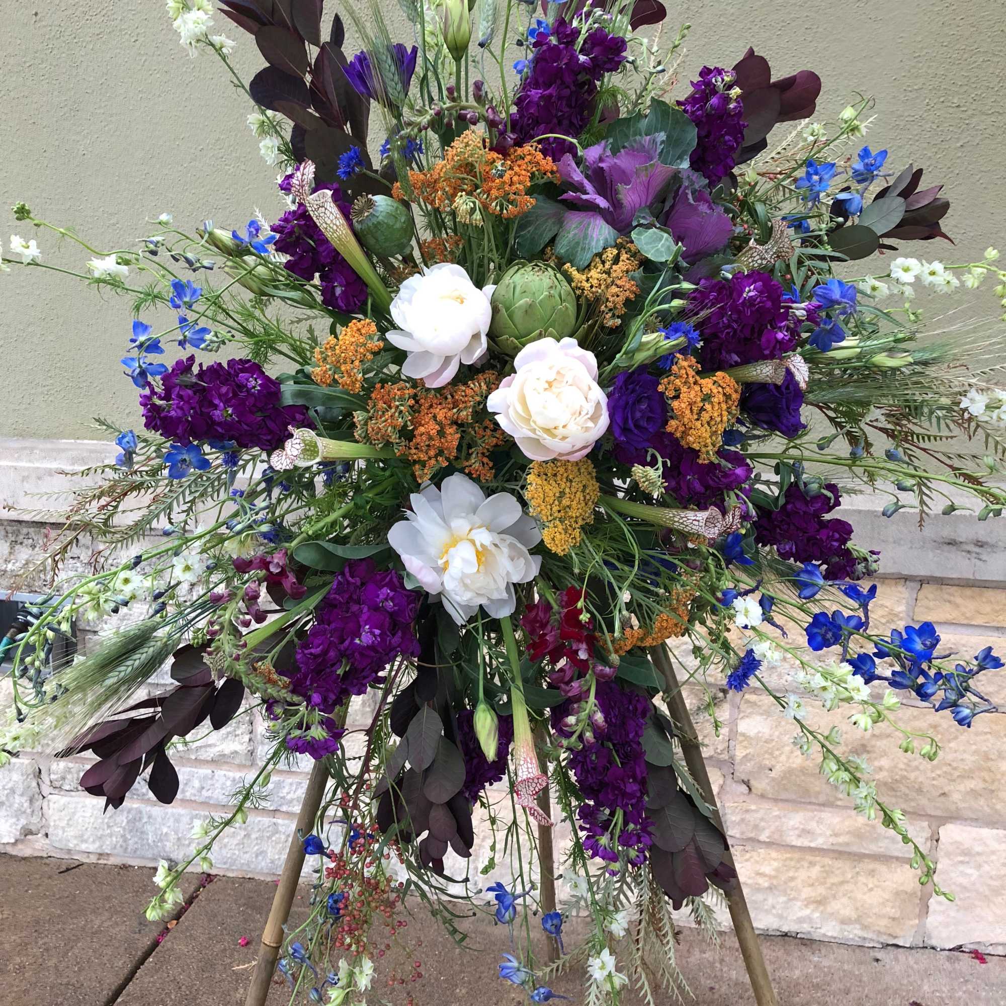 Large standing floral spray with purple, white, and blue blooms