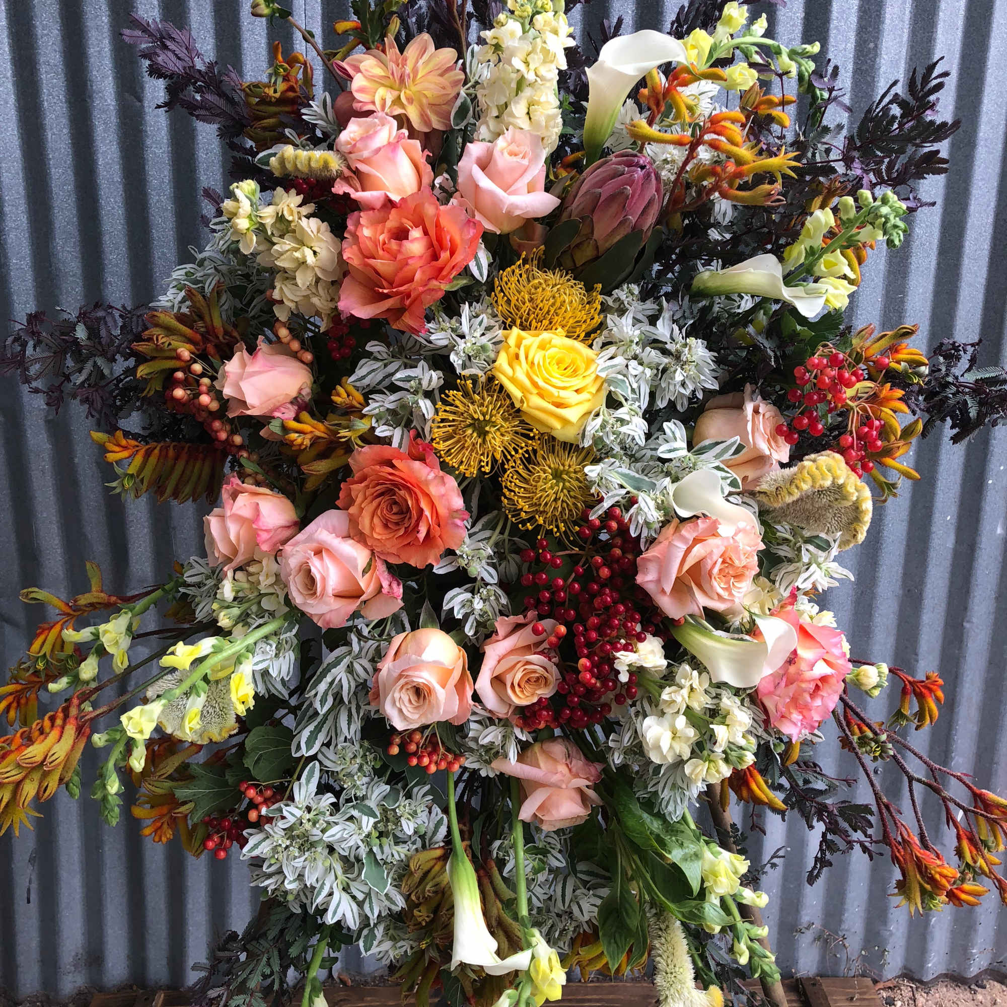 Large mixed floral arrangement with pink roses, white calla lilies, and yellow blooms