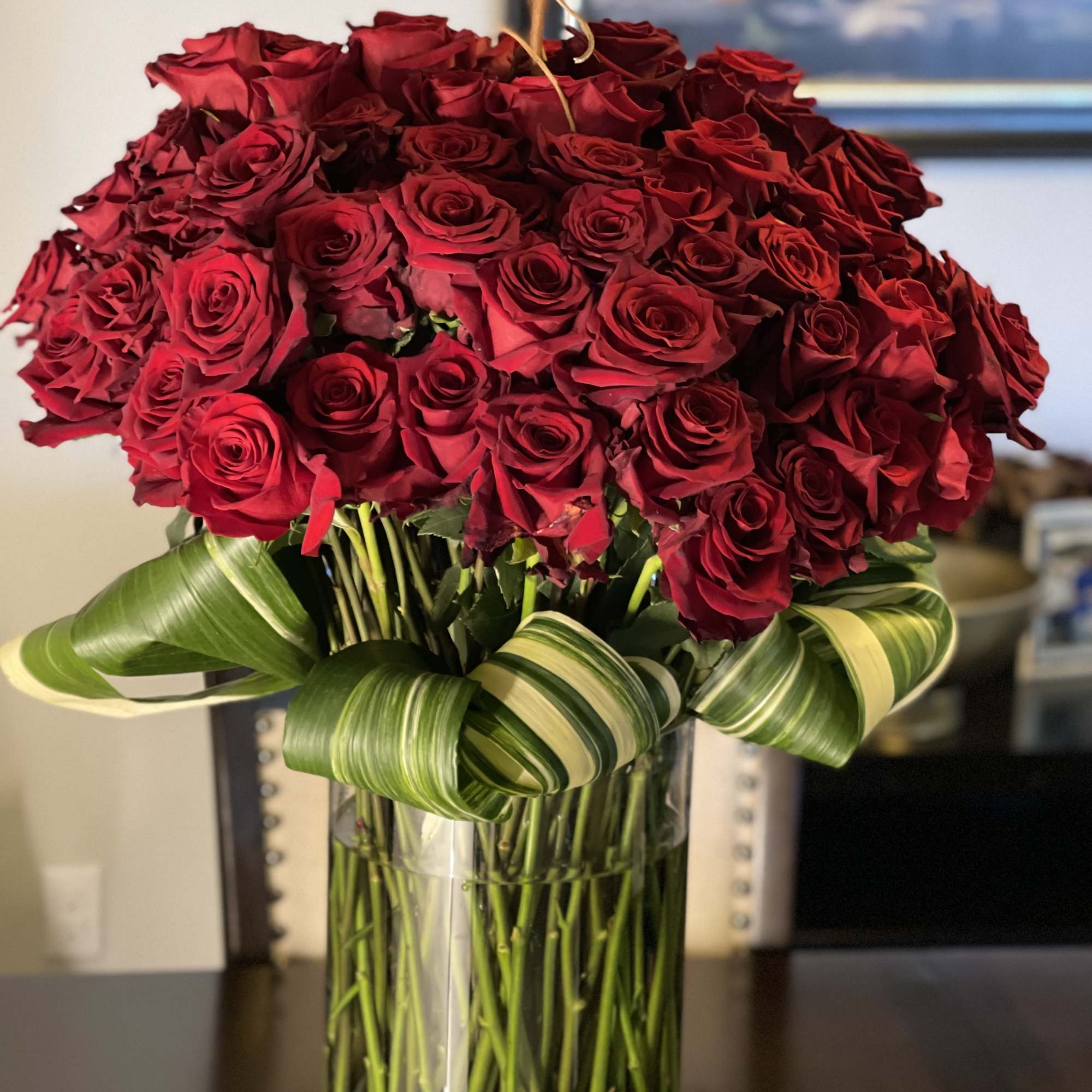 Bouquet of red roses in a clear glass vase with striped ribbon