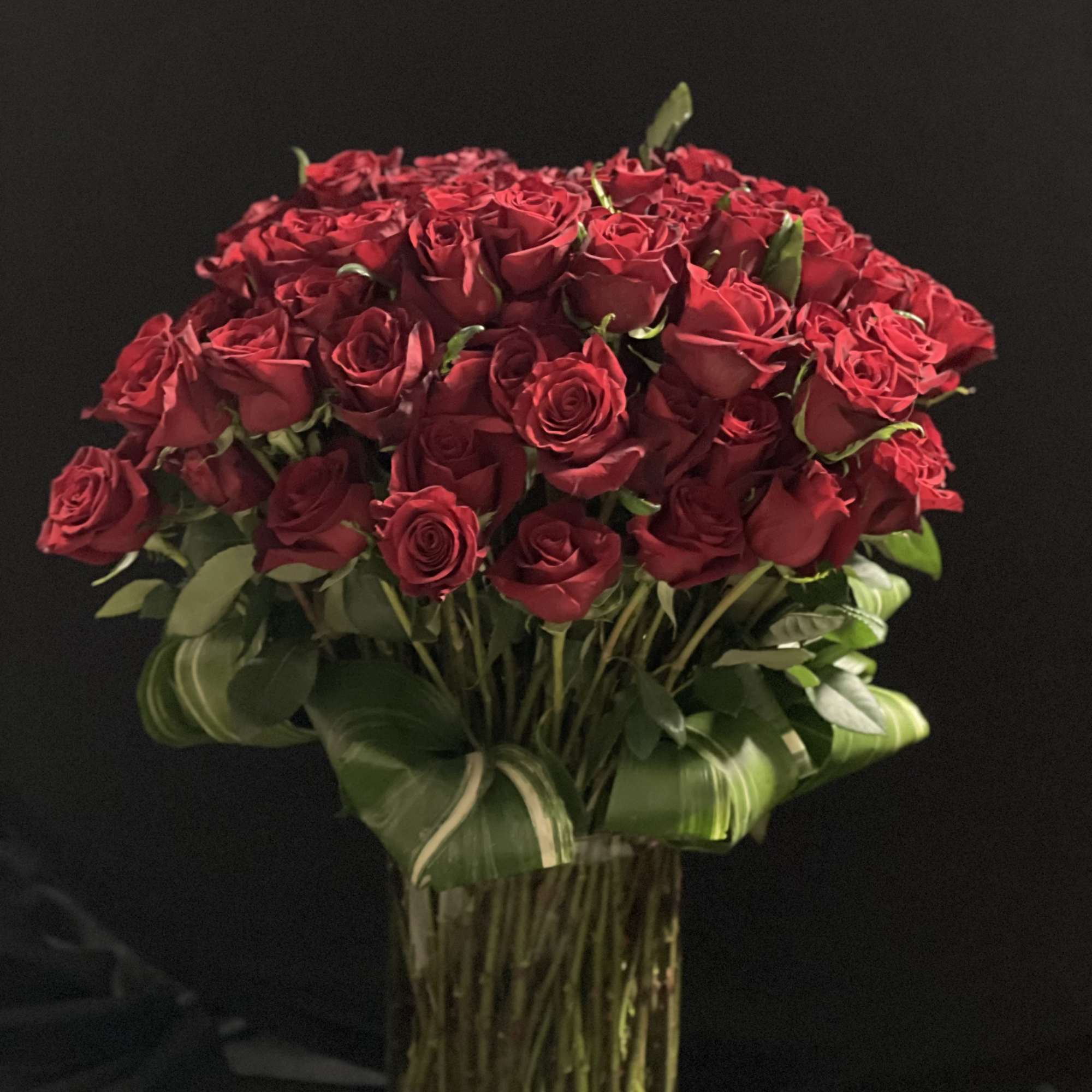 Bouquet of red roses in a tall glass vase
