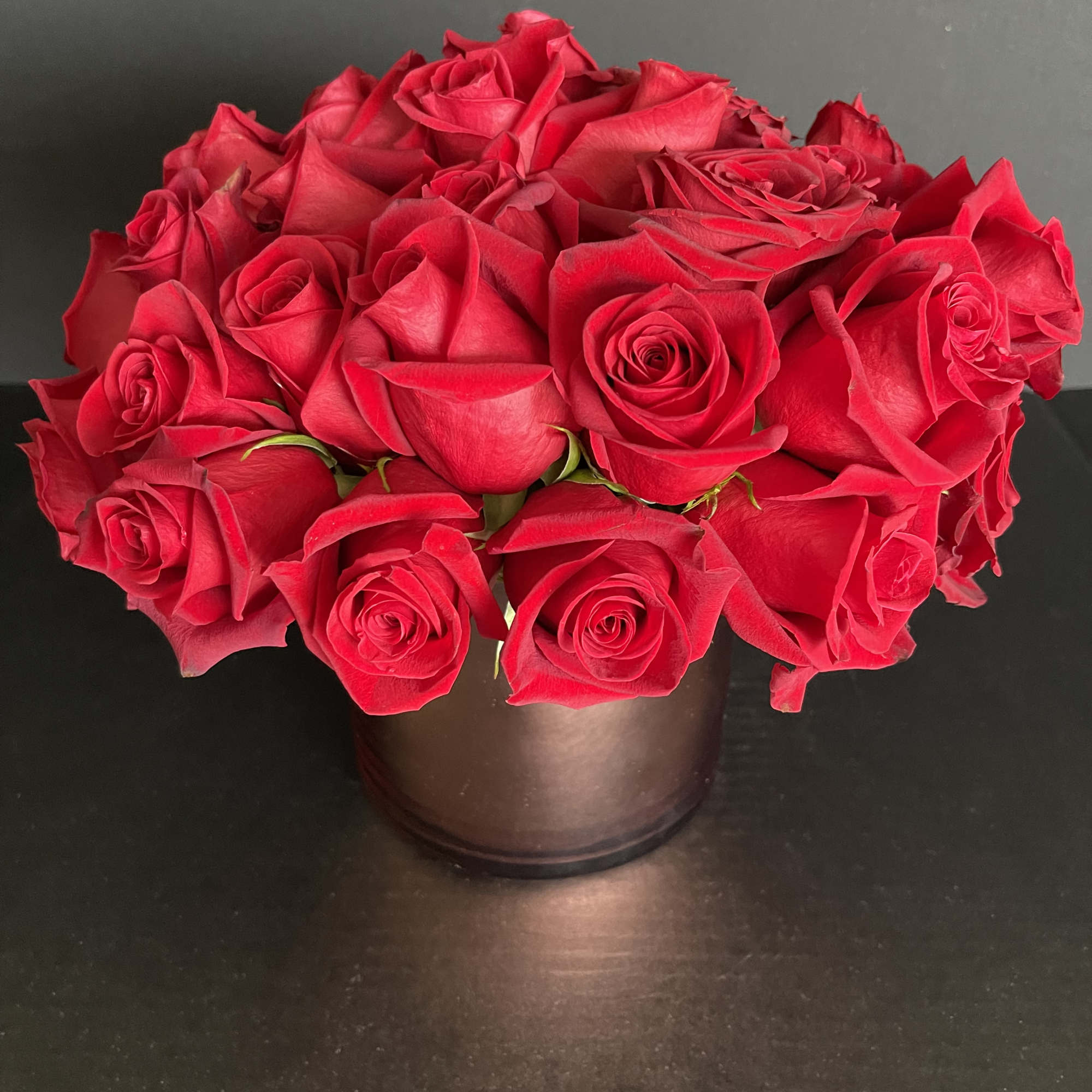 Red rose bouquet in a dark round vase