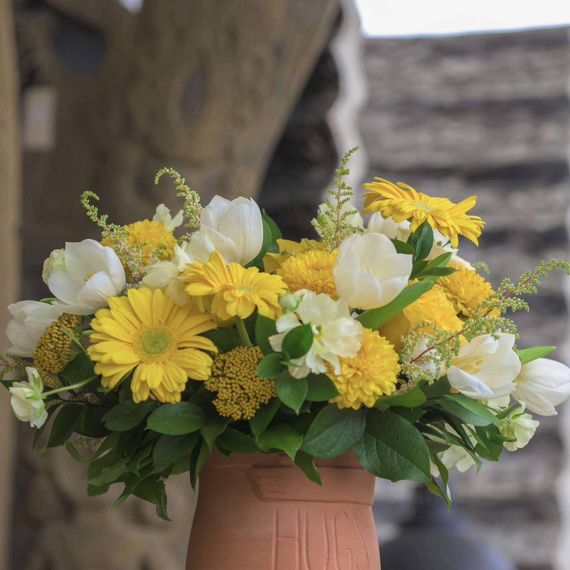 Yellow and white flower arrangement in a terracotta vase