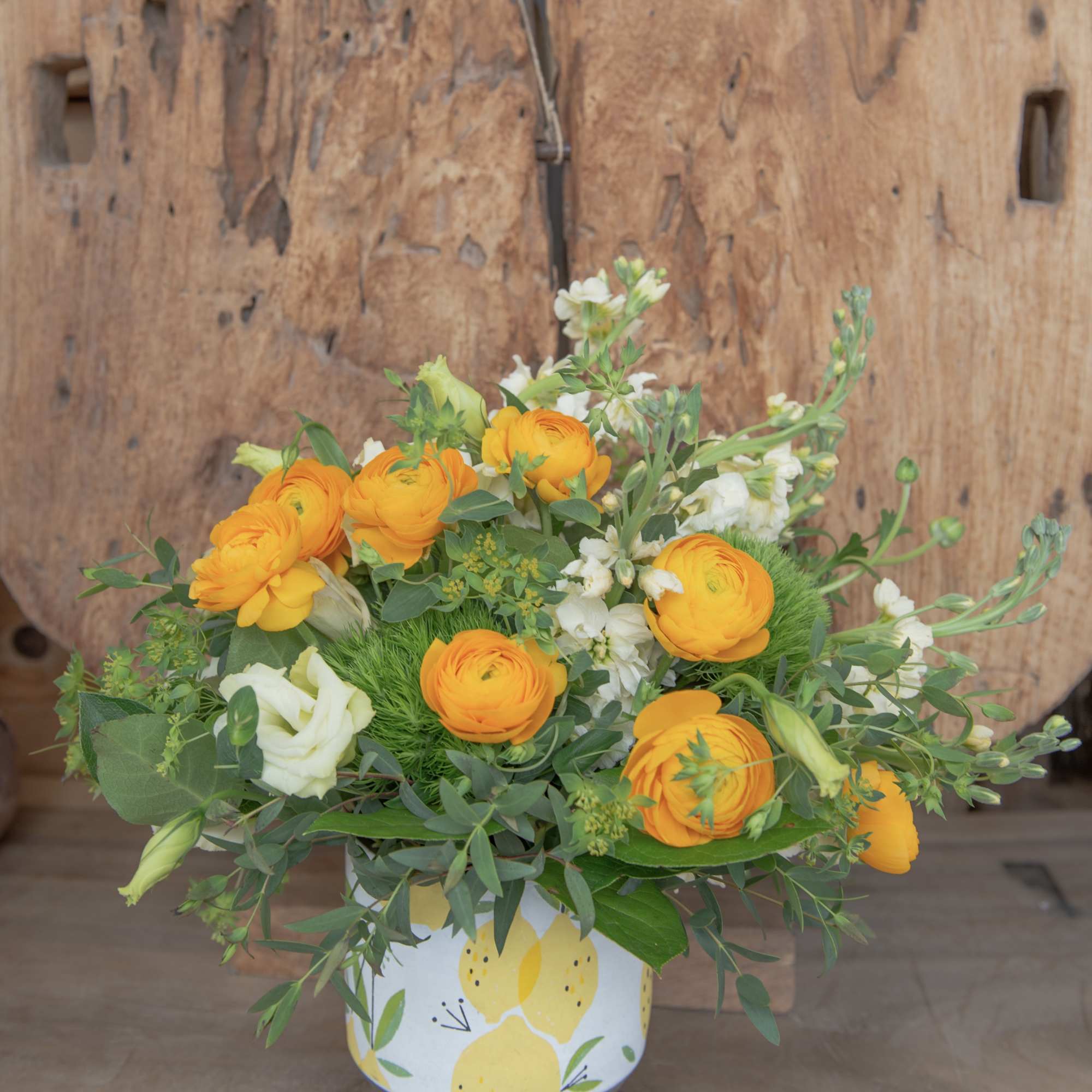 Orange and white flowers arranged in a lemon-patterned vase