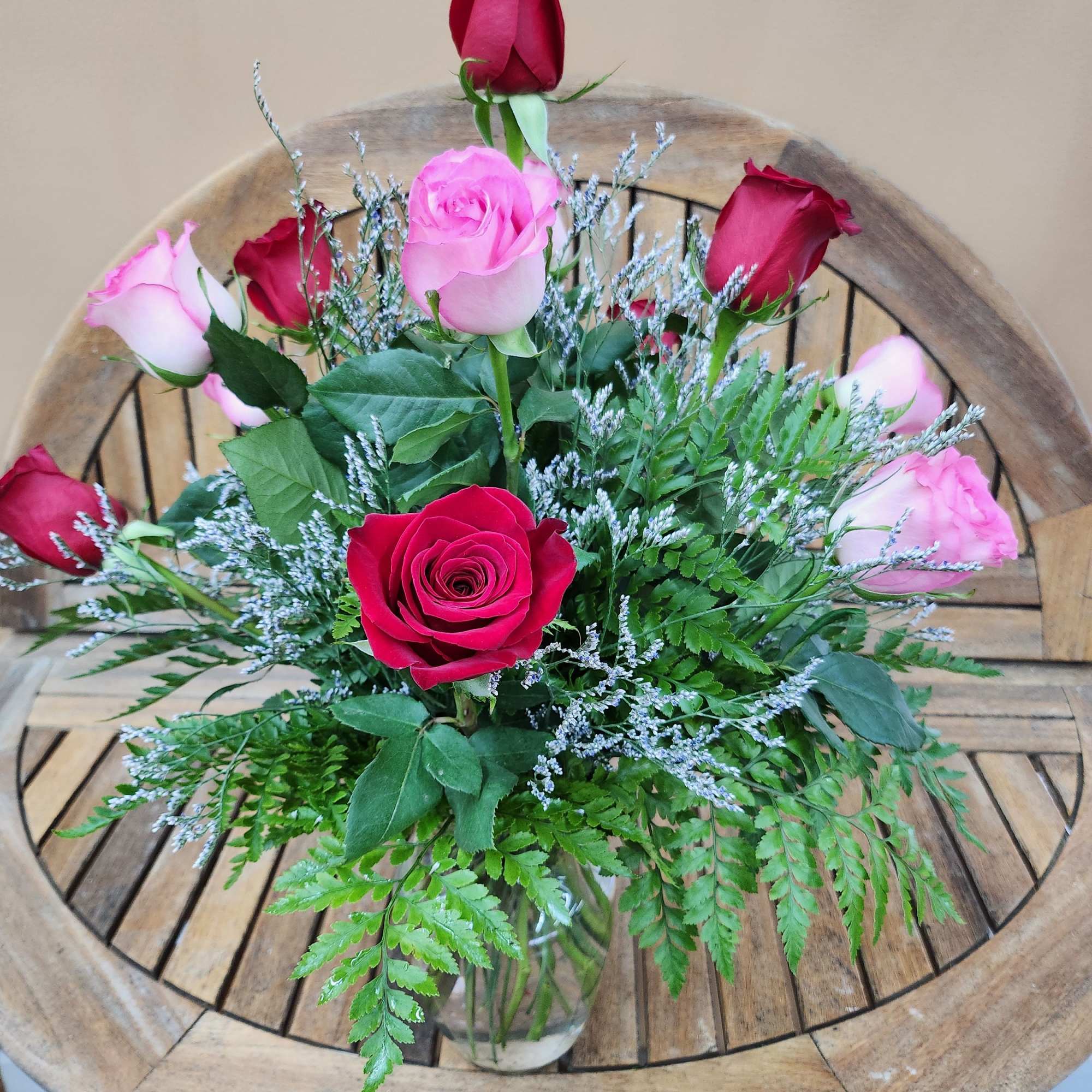 Dozen mixed rones in pink and red. Arranged in vase with greens