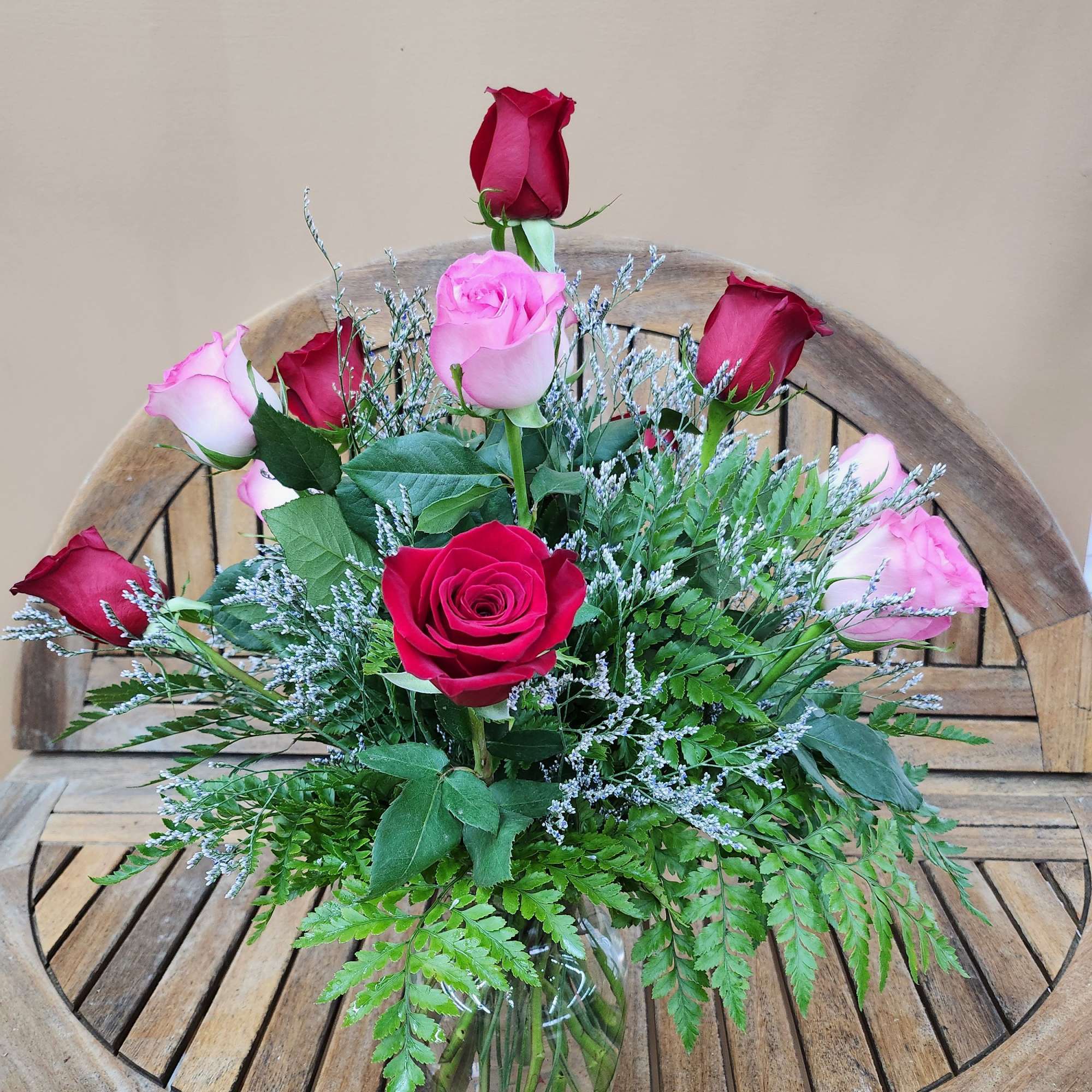 Dozen mixed rones in pink and red. Arranged in vase with greens