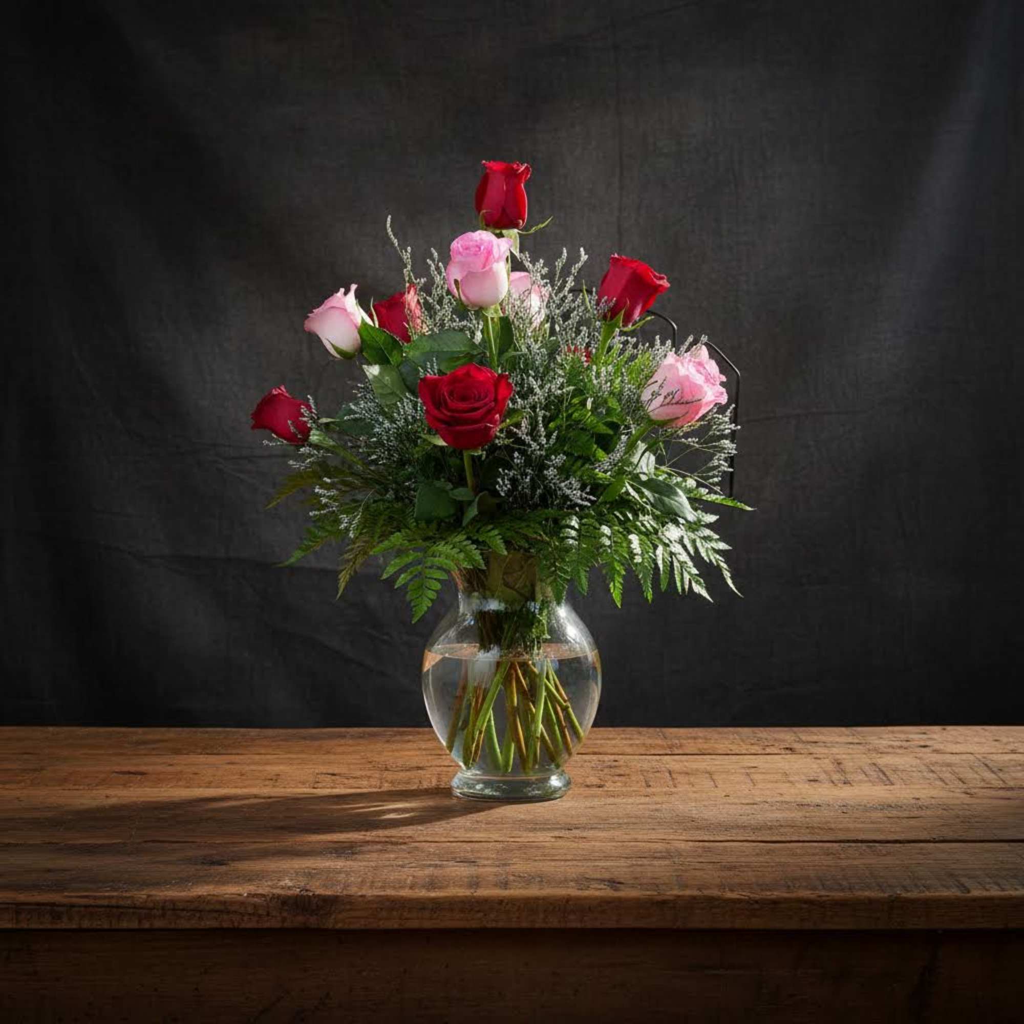 Dozen mixed rones in pink and red. Arranged in vase with greens