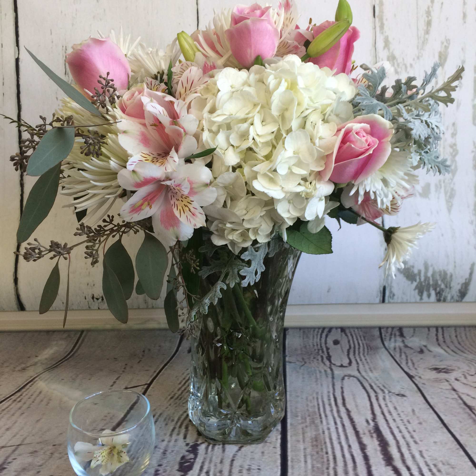 Pink roses and white hydrangeas arranged in a clear glass vase