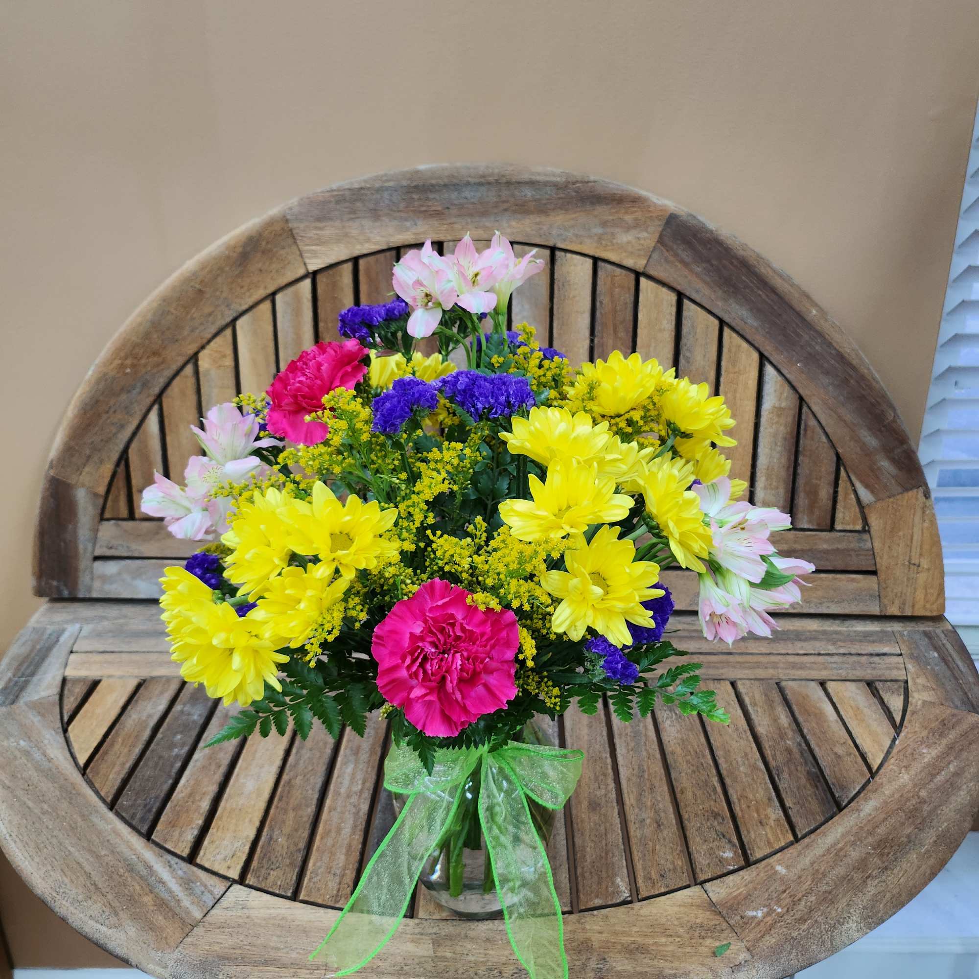 Colorful mixed bouquet in a clear glass vase with a green ribbon