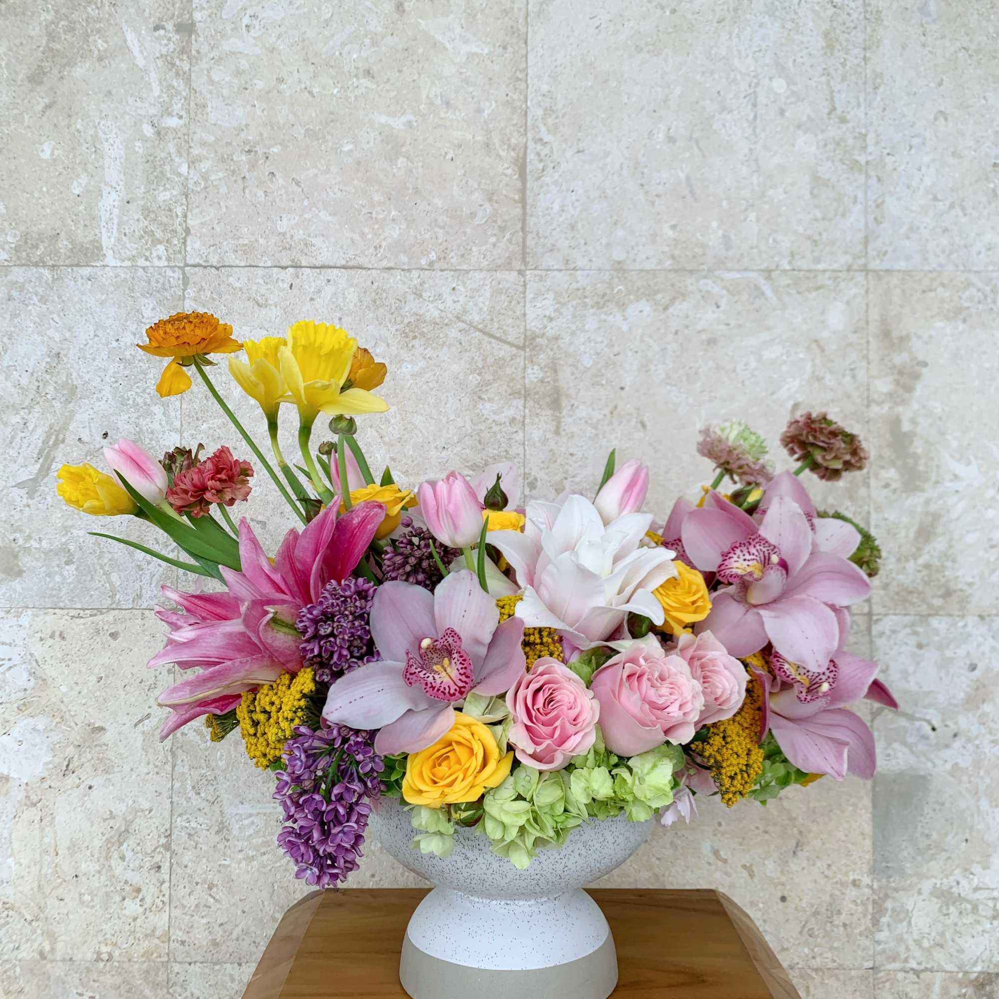 Mixed pink, yellow, and purple flowers in a white vase