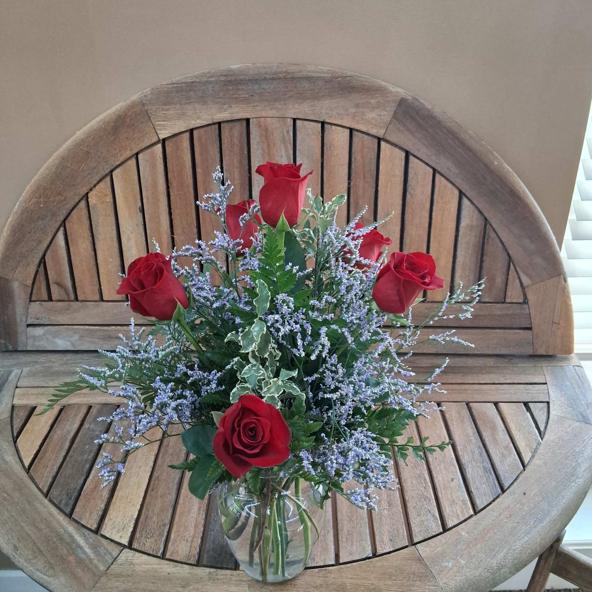 Red roses and lavender filler flowers in a clear glass vase