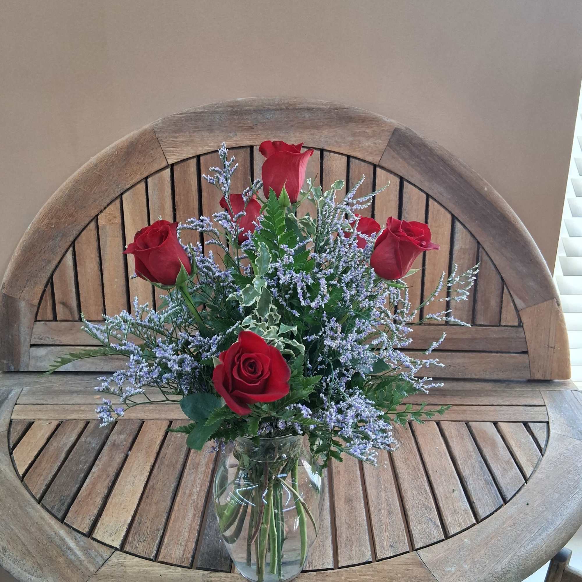 Red roses and lavender filler flowers in a clear glass vase