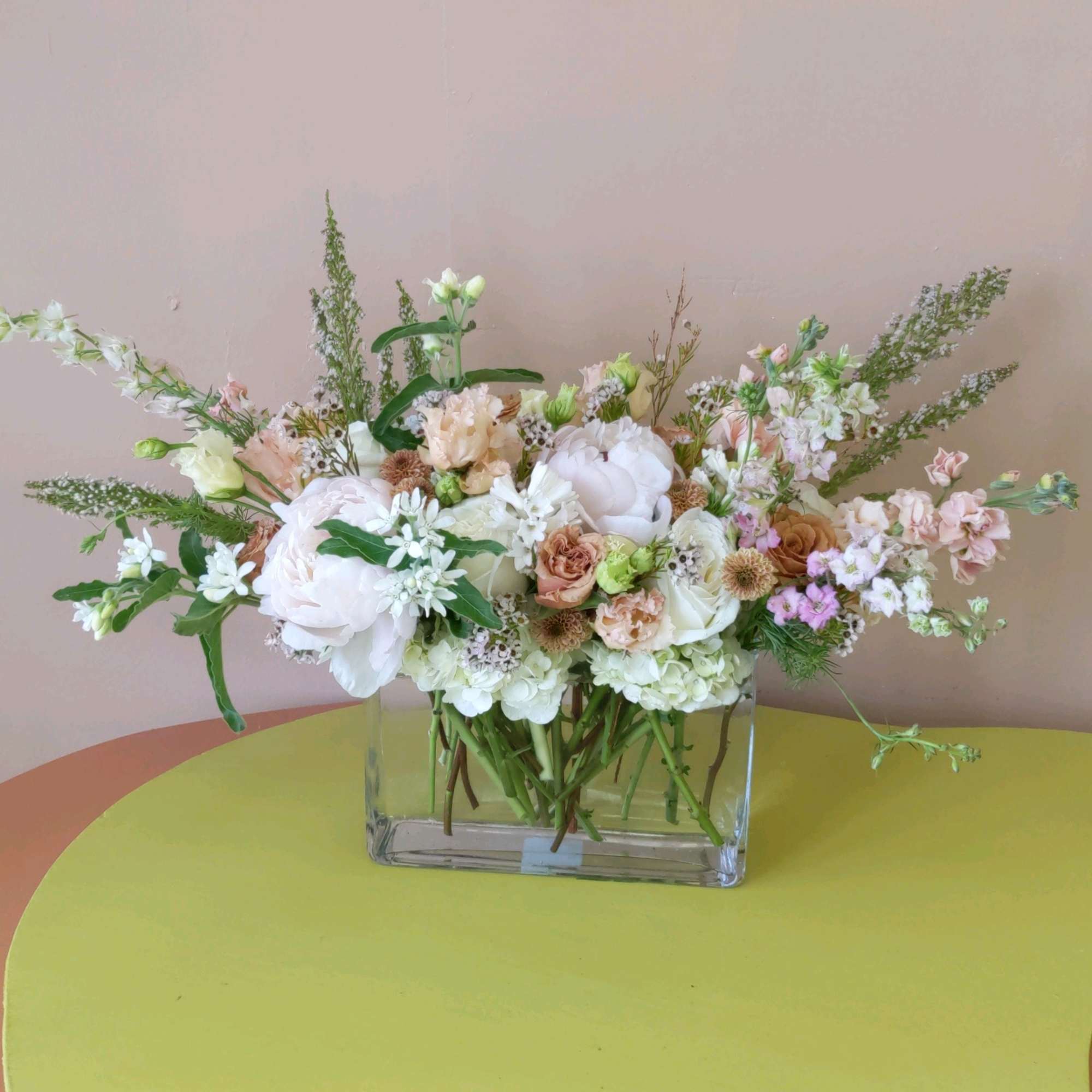 Pastel mixed flower arrangement in a clear rectangular vase