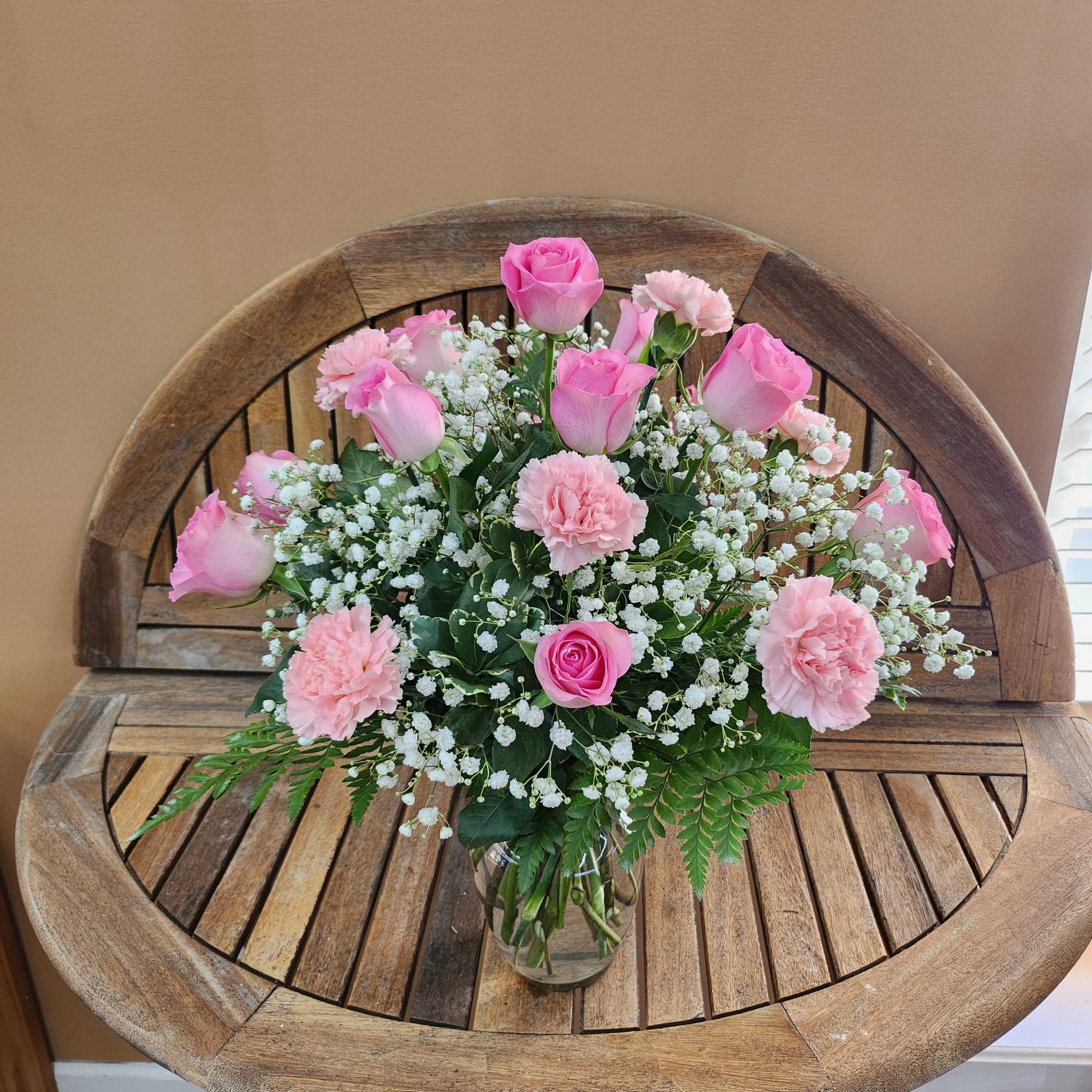 Pink roses and carnations in a glass vase with baby's breath