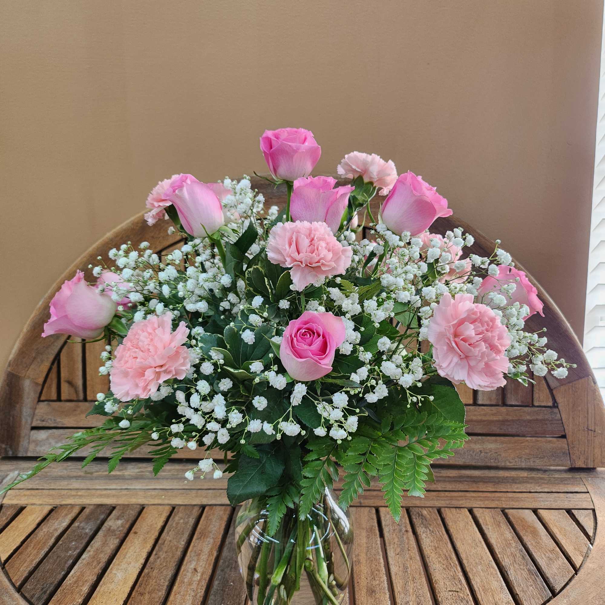 Pink roses and carnations in a clear glass vase with white baby's breath