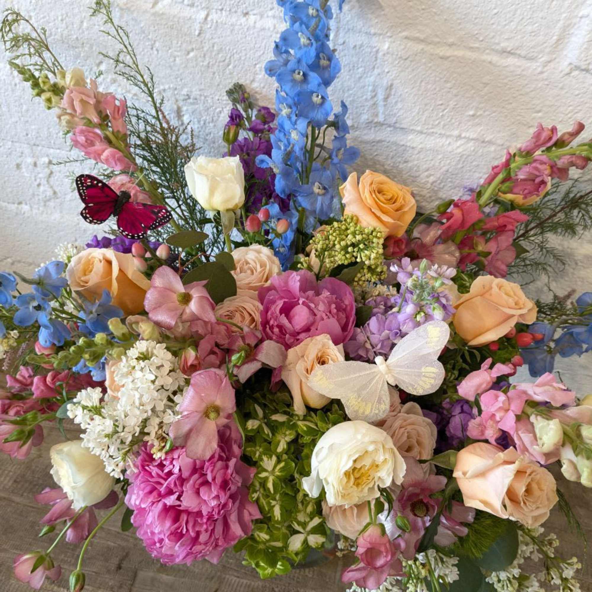 Colorful mixed bouquet with roses, peonies, and tall blue blooms