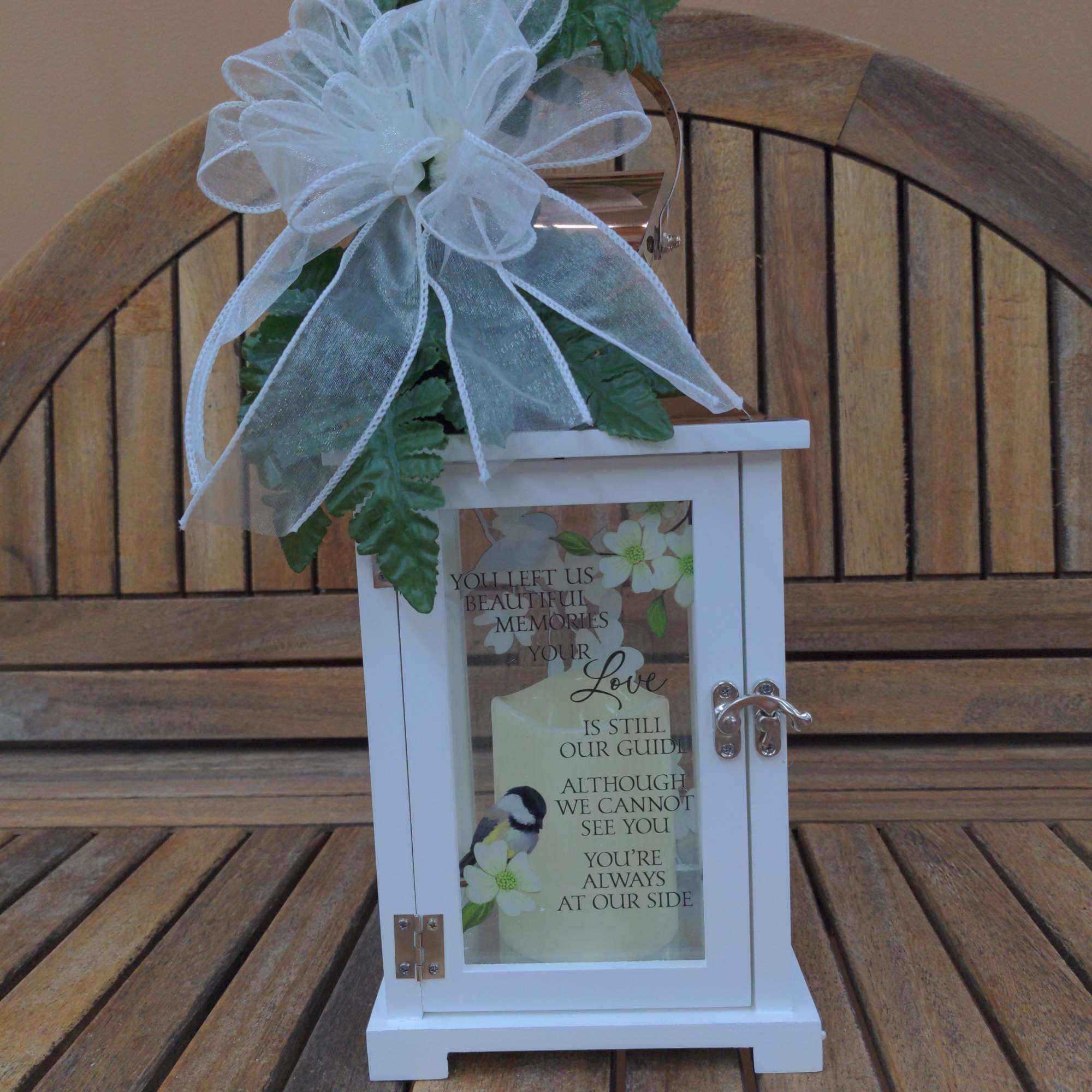 White memorial lantern with a large bow and greenery on top