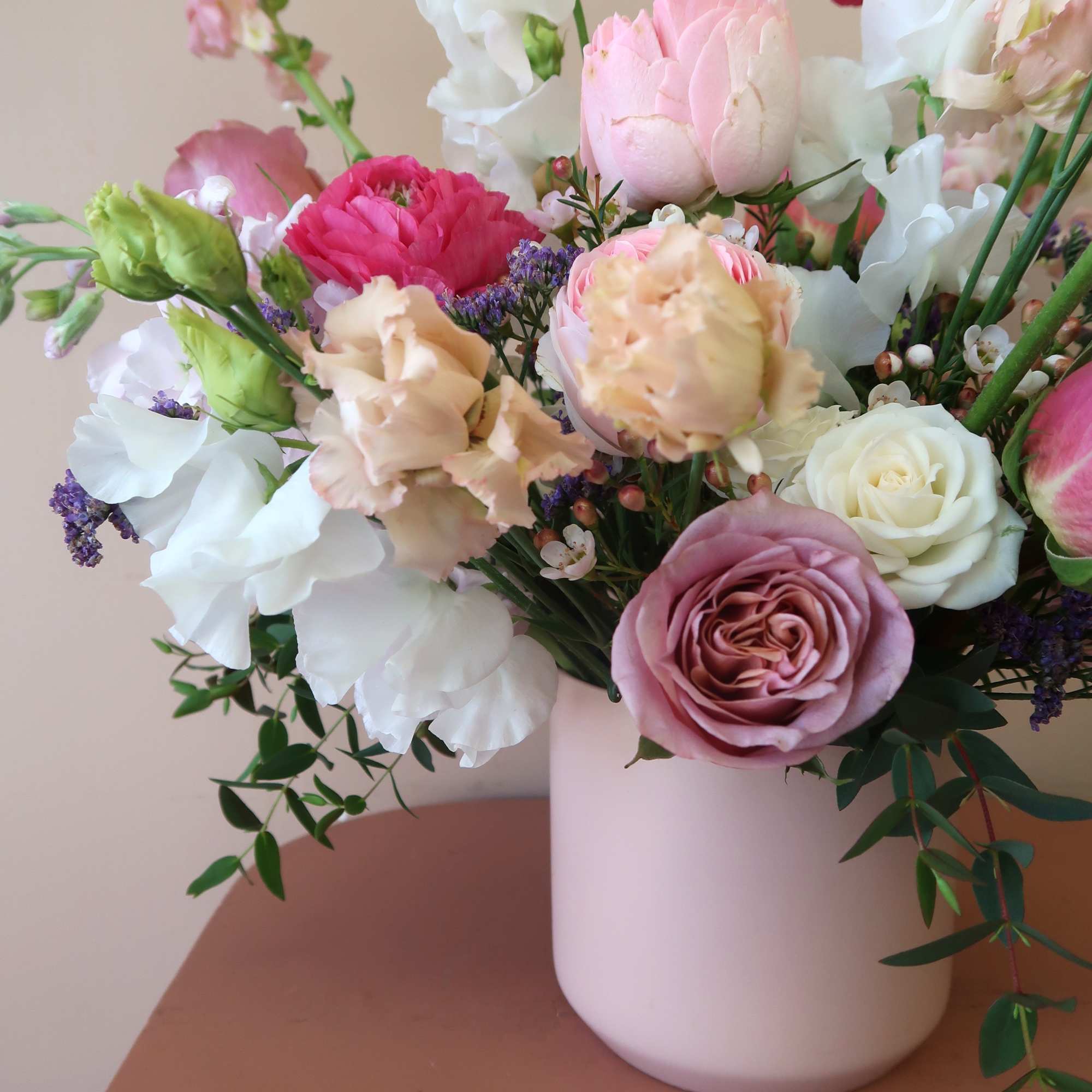 Mixed pastel bouquet in a white vase with roses and ruffled blooms