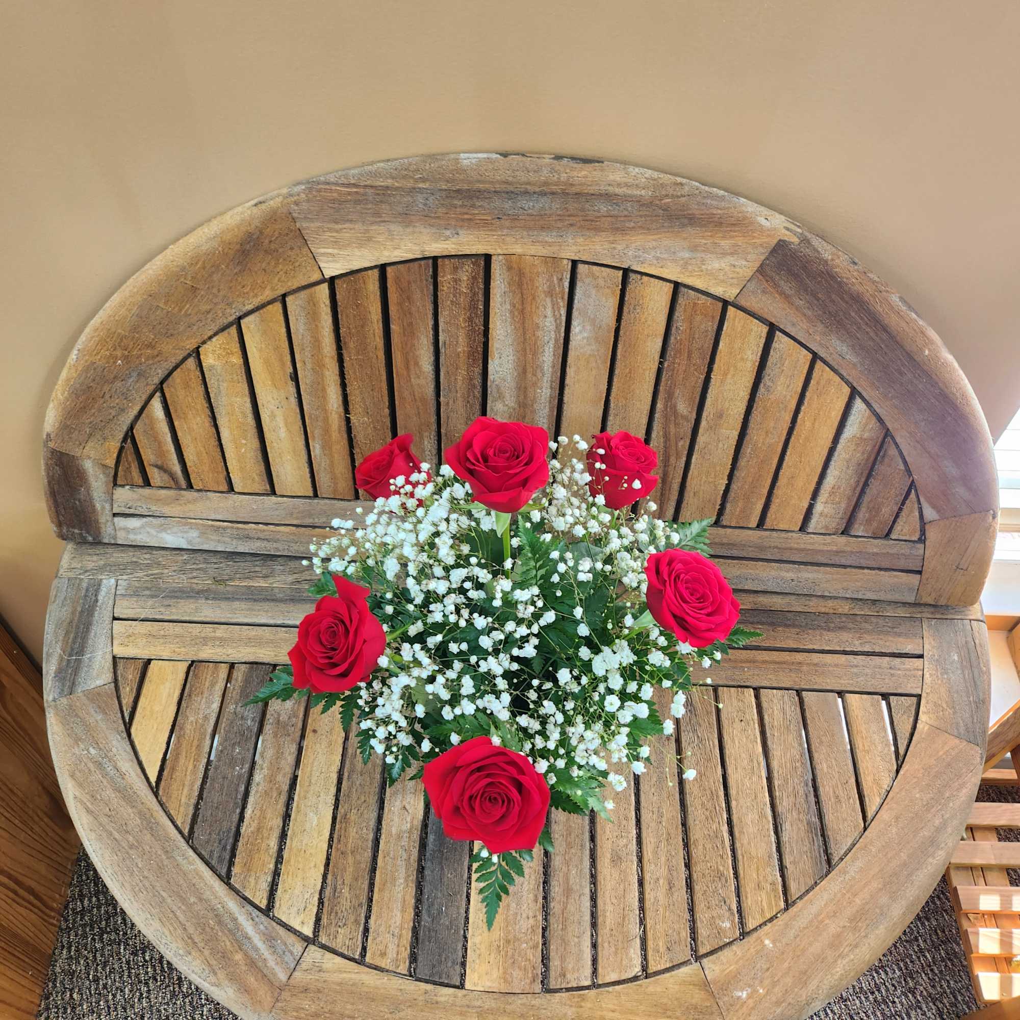 Red roses with white baby's breath arranged on a wooden table