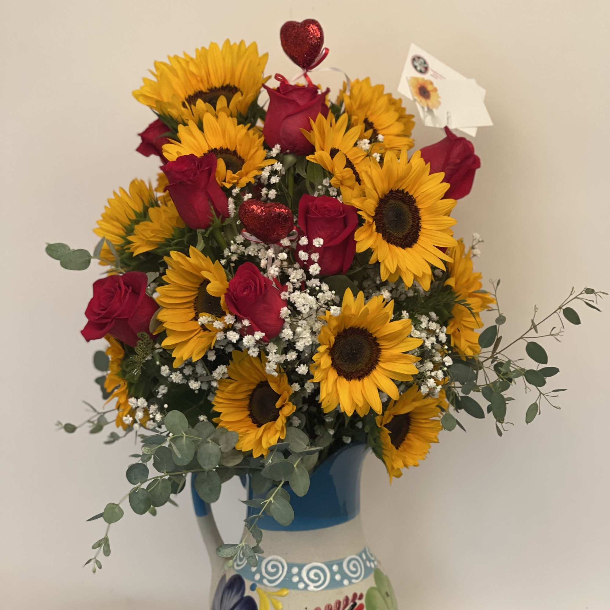 Bouquet of sunflowers and red roses in a painted ceramic vase