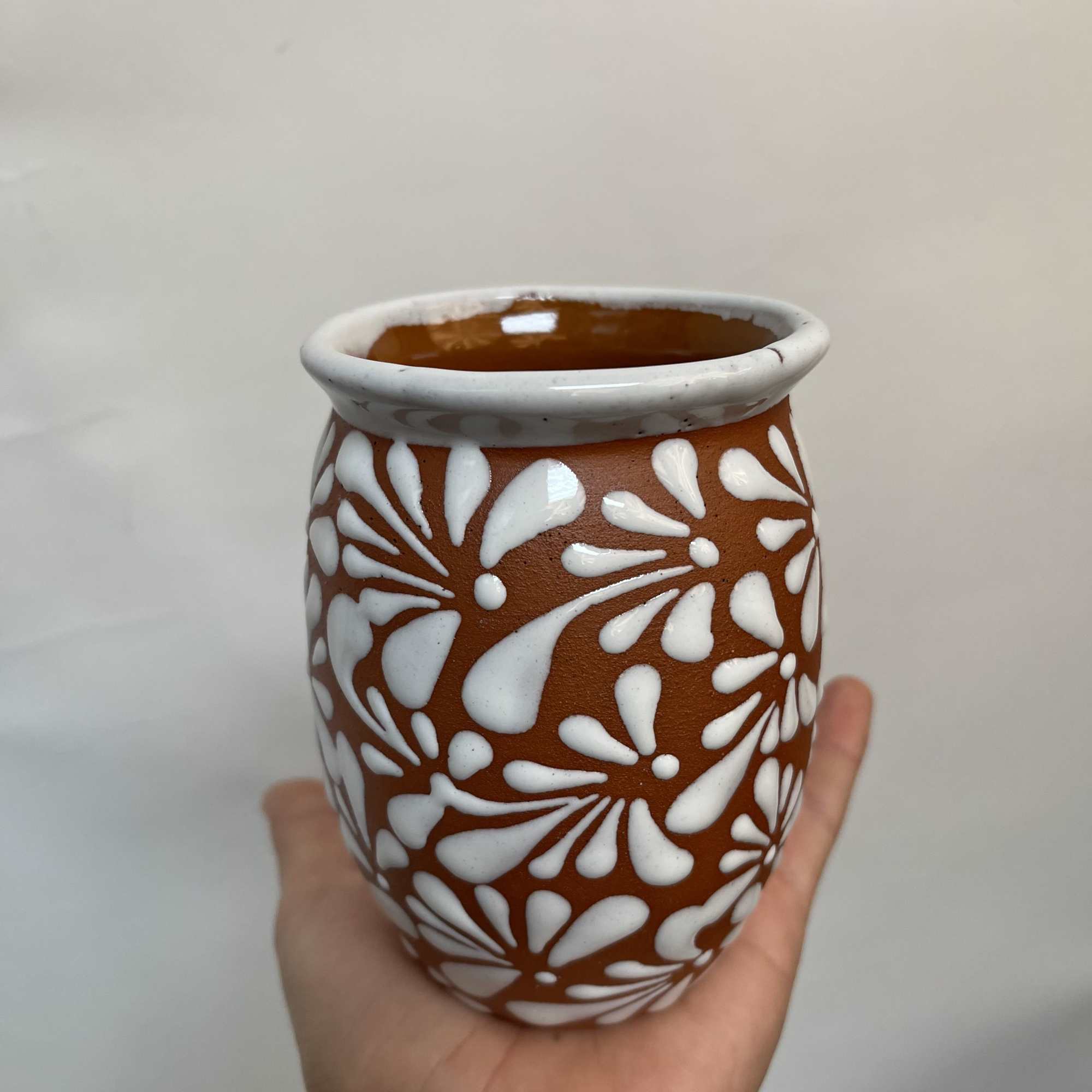Hand holding a small patterned ceramic vase