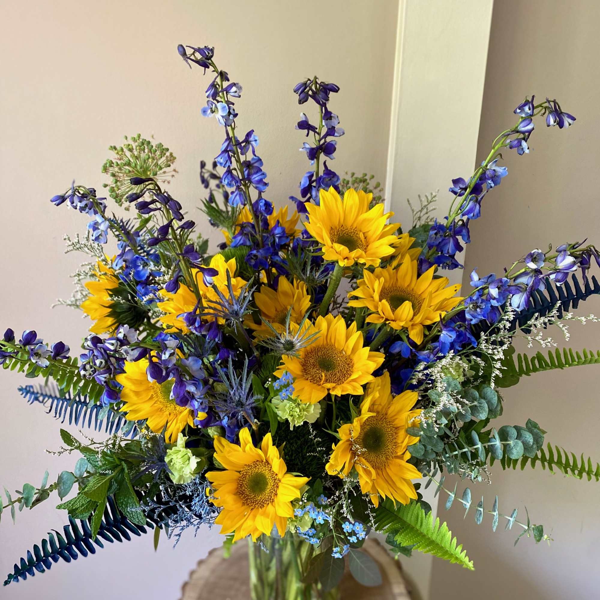 Bouquet of yellow sunflowers and blue flowers in a glass vase