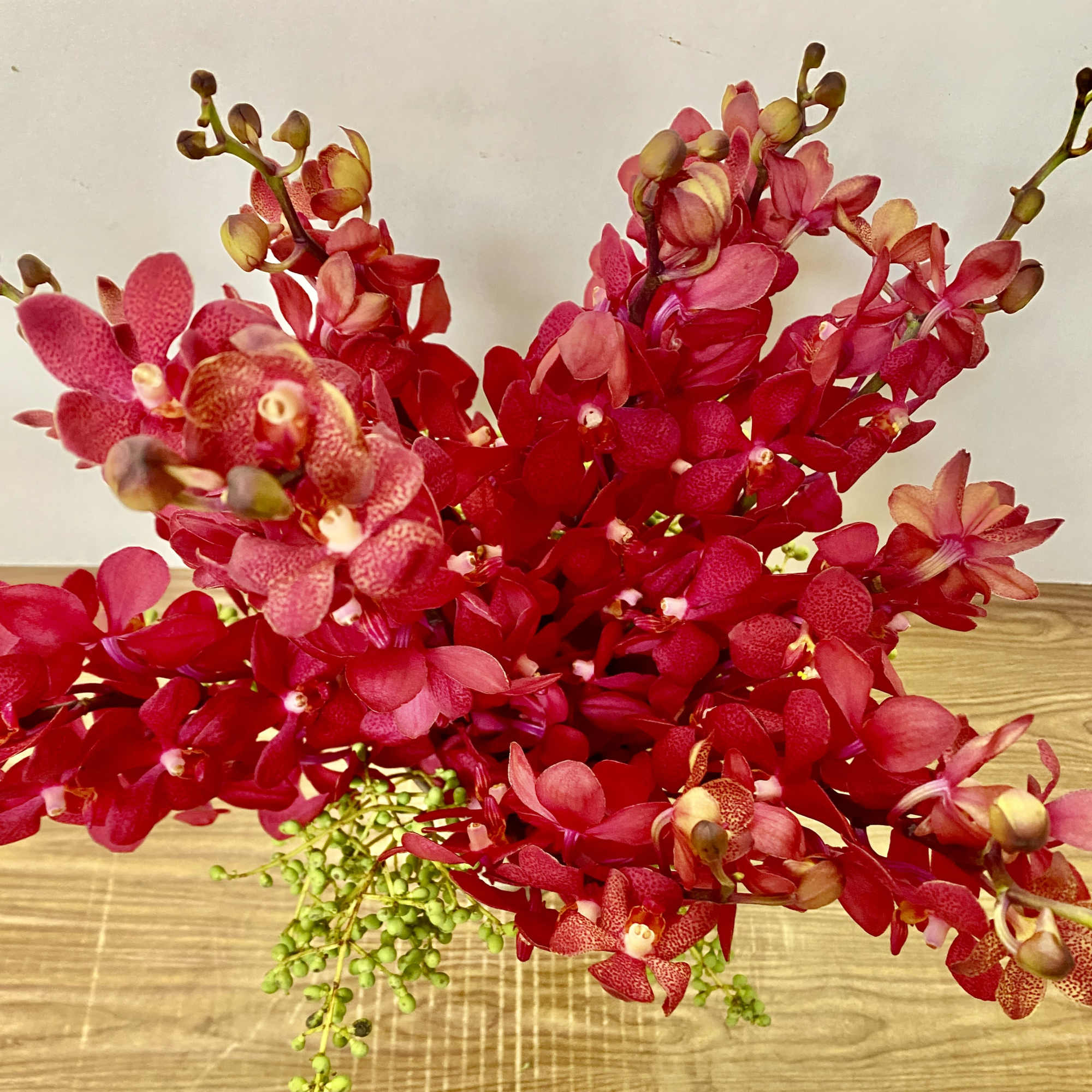 Red orchid arrangement with green accents on a table