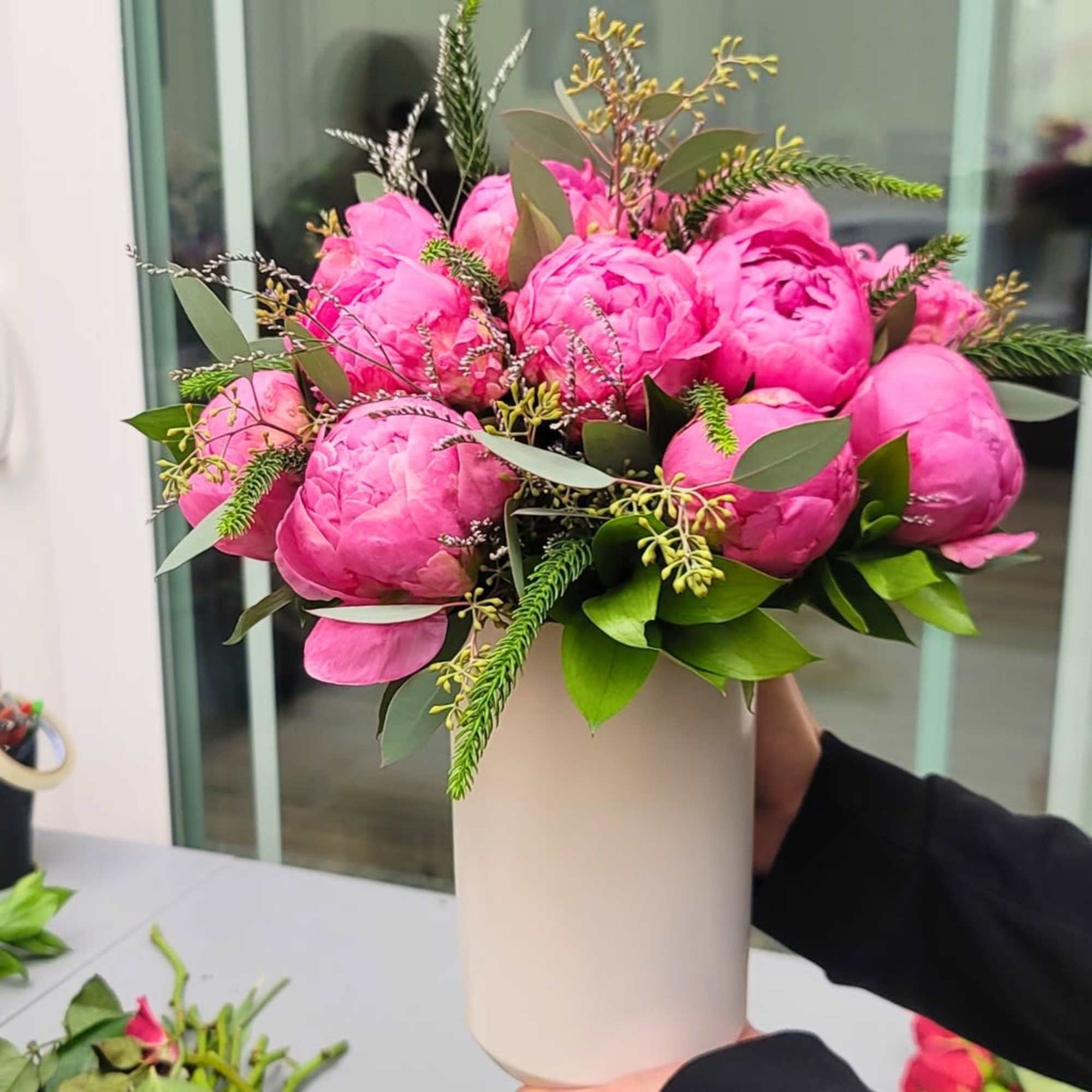 Pink peonies arranged in a tall white vase