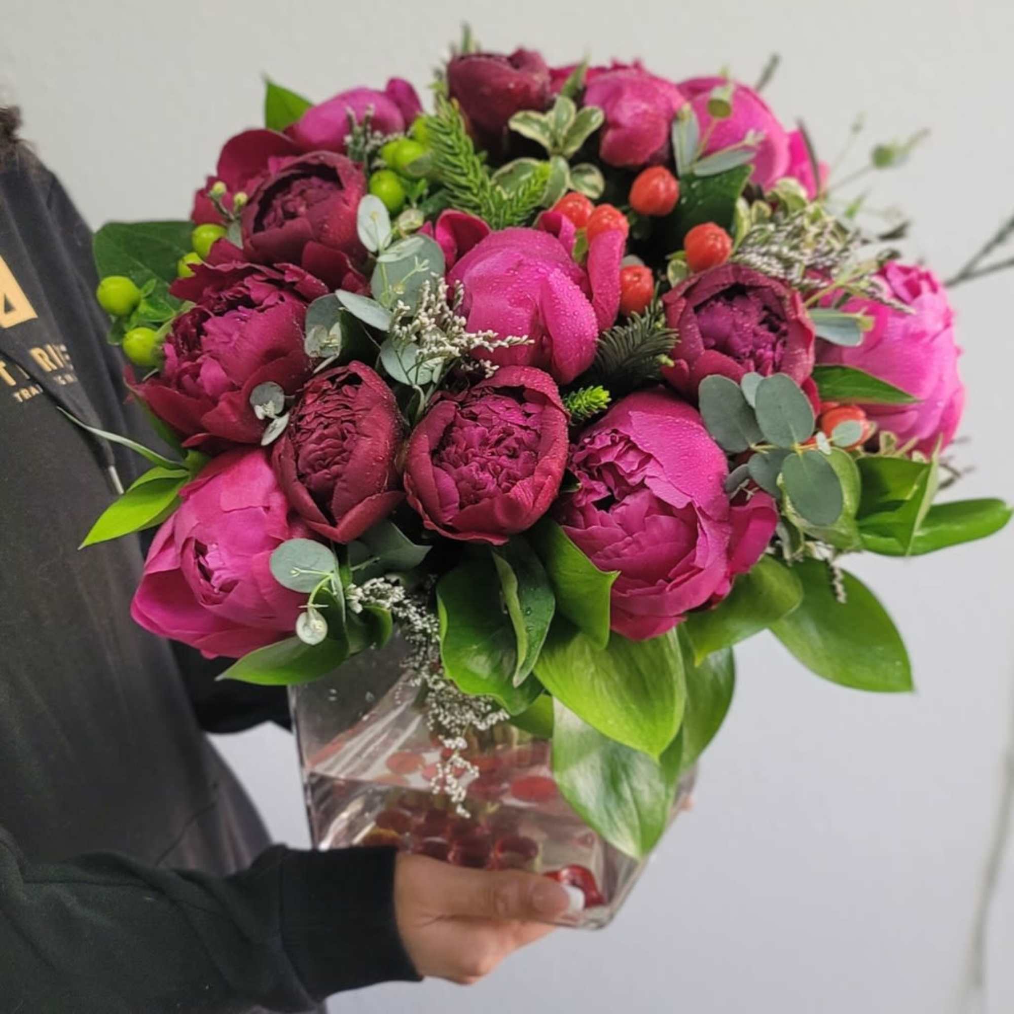 Bouquet of magenta peonies and dark burgundy blooms in a clear wrap
