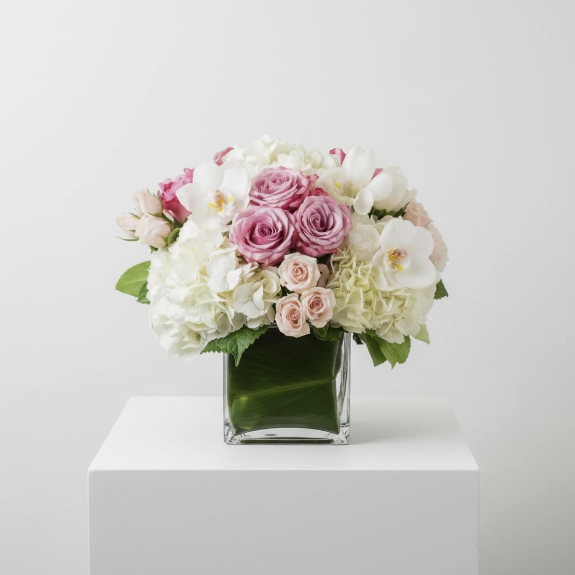 A lush cluster of white hydrangeas and creamy white orchids creates the