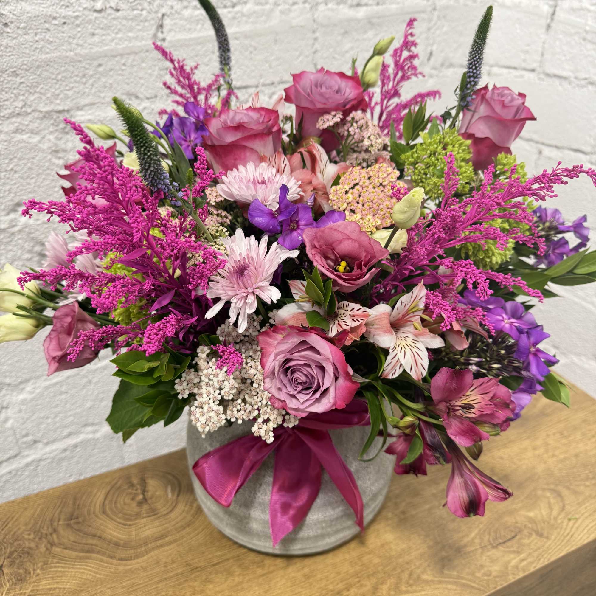 Pink and purple mixed bouquet in a gray vase with a satin ribbon