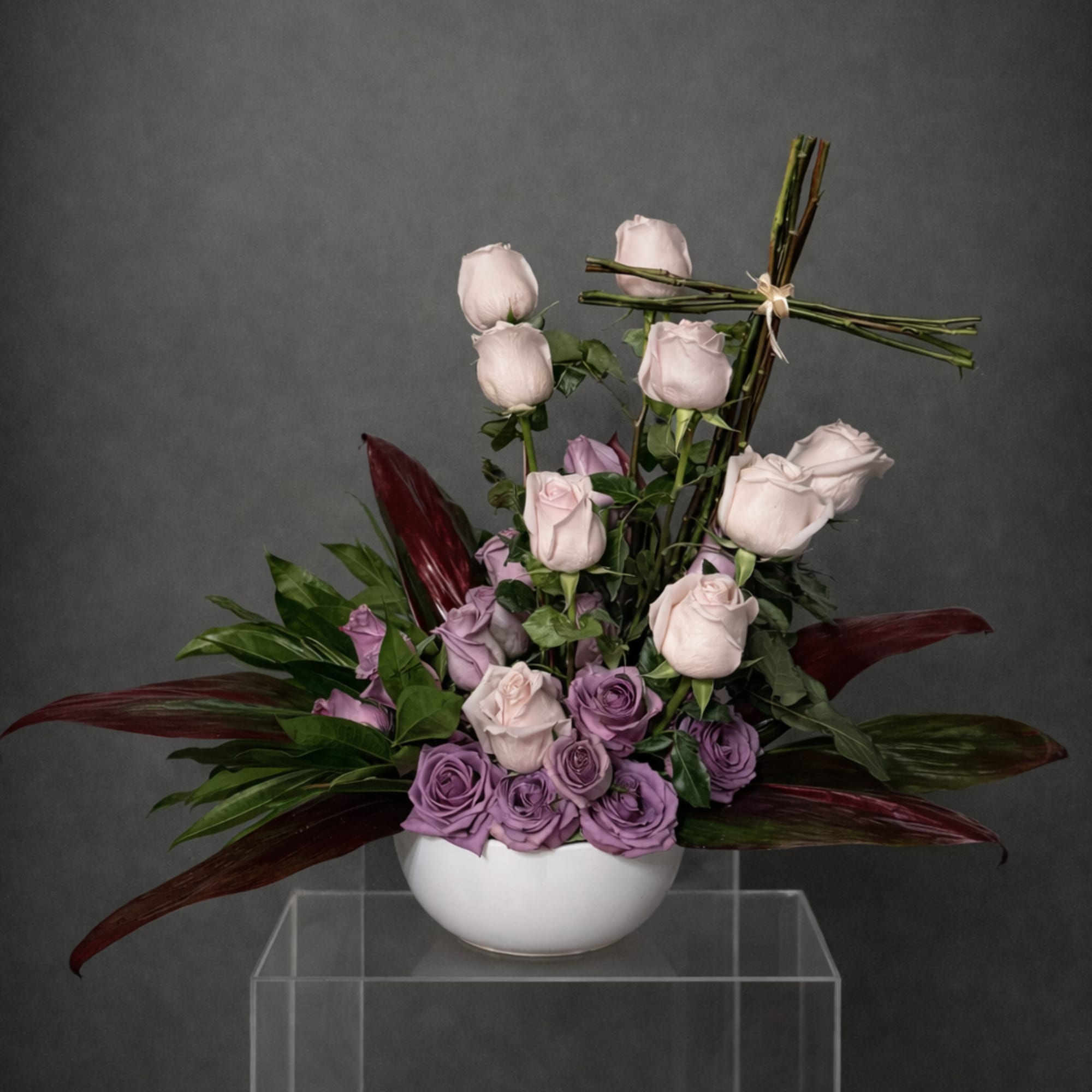 Lavender and pale pink roses arranged in a white bowl vase