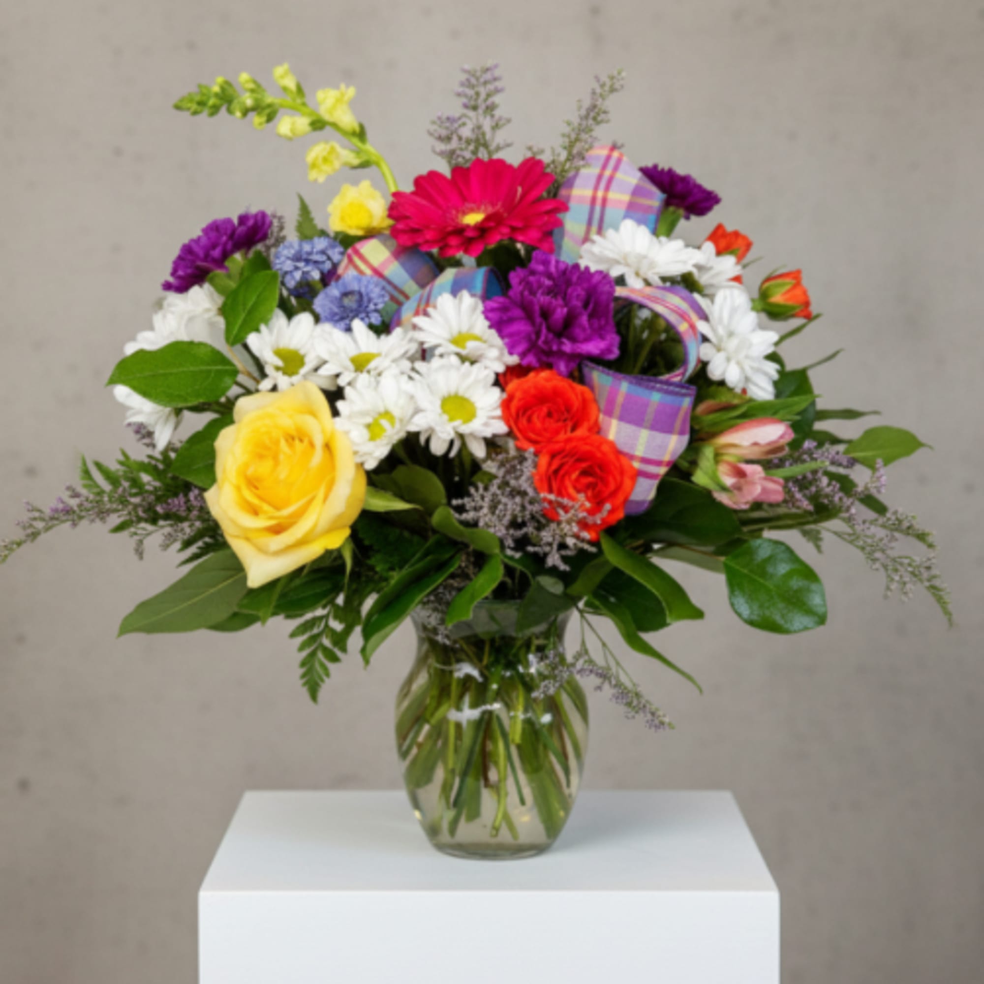Fresh bright mixed blooms arranged in a clear container.