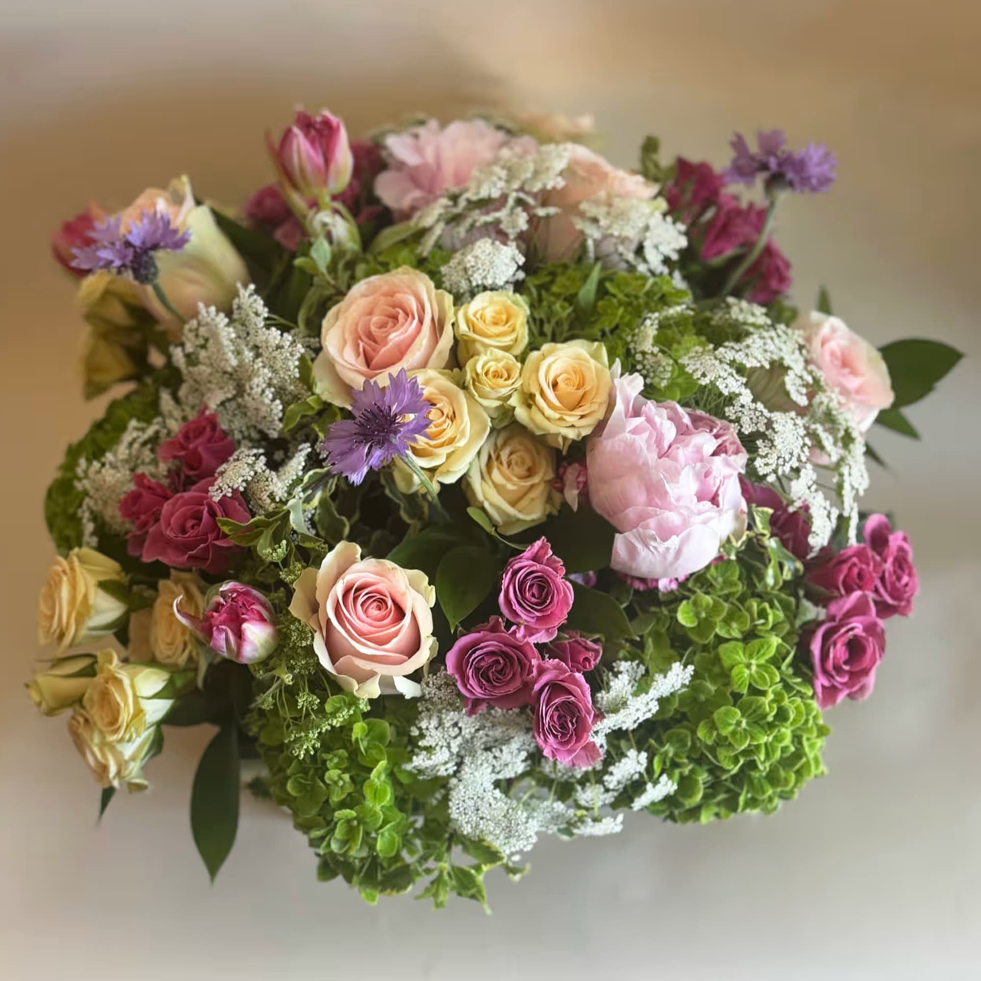 Mixed bouquet of roses, peonies, and purple accent flowers