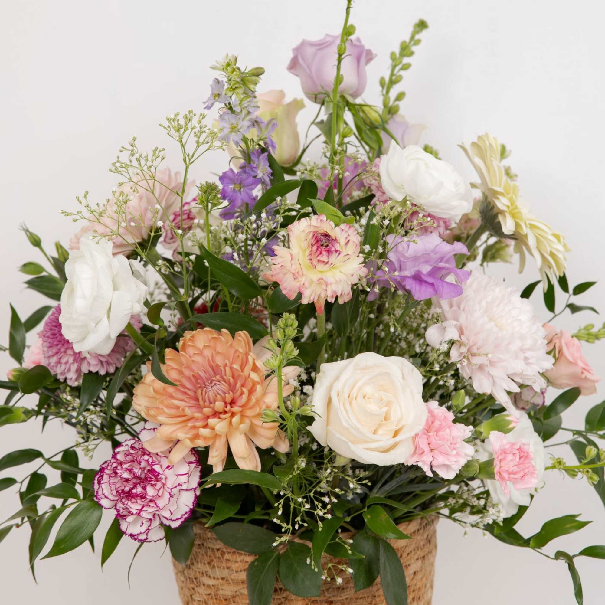 Mixed pastel flower arrangement in a woven basket