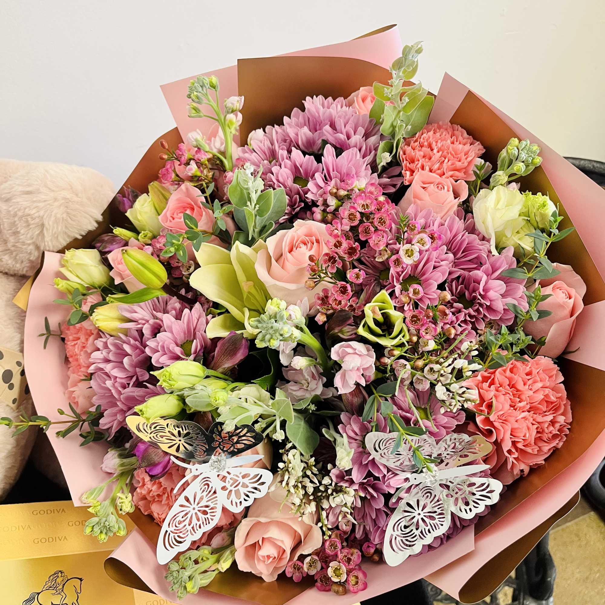 Pink and coral bouquet with roses, chrysanthemums, and lilies in pink-brown wrap