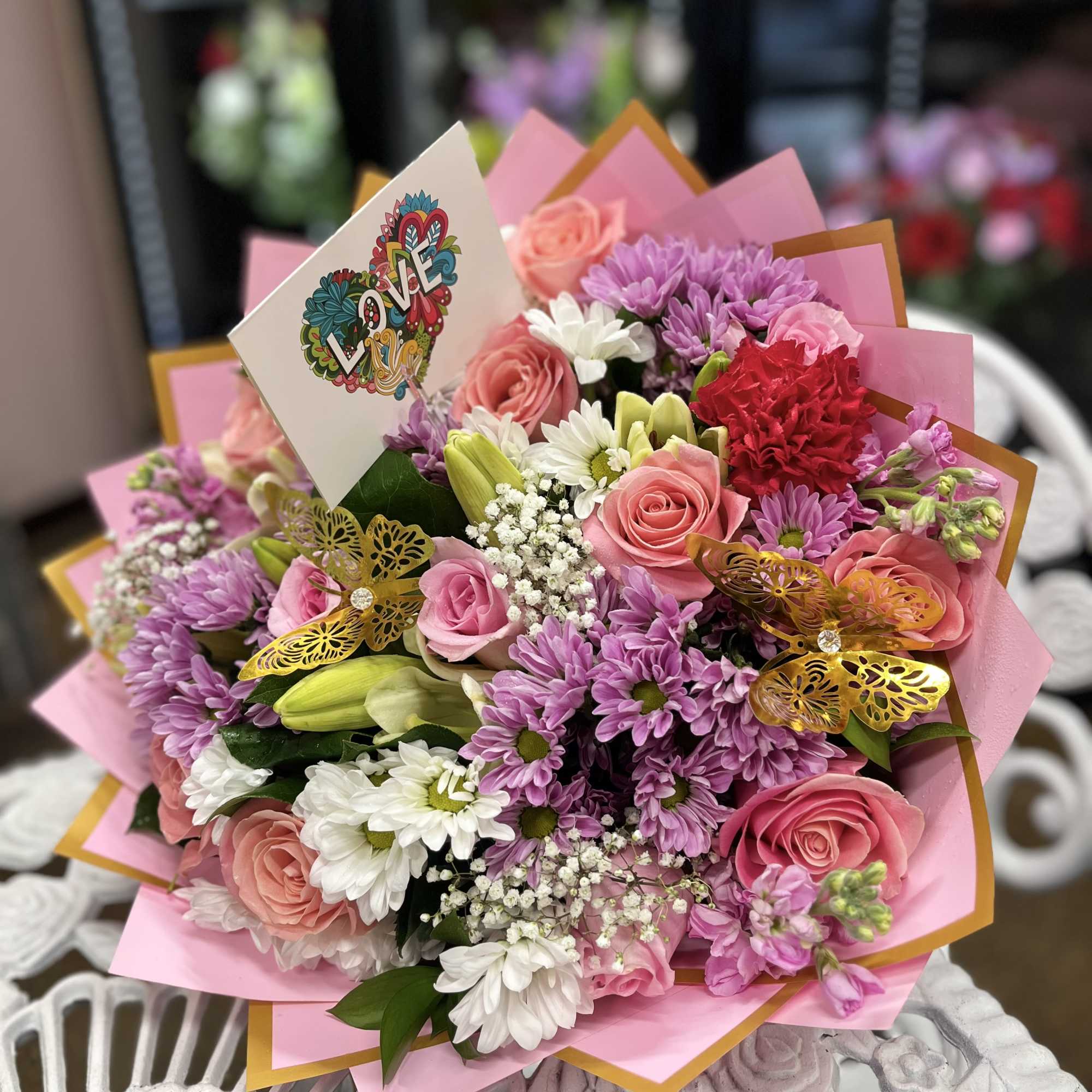 Pink and purple bouquet with roses, daisies, and a LOVE card